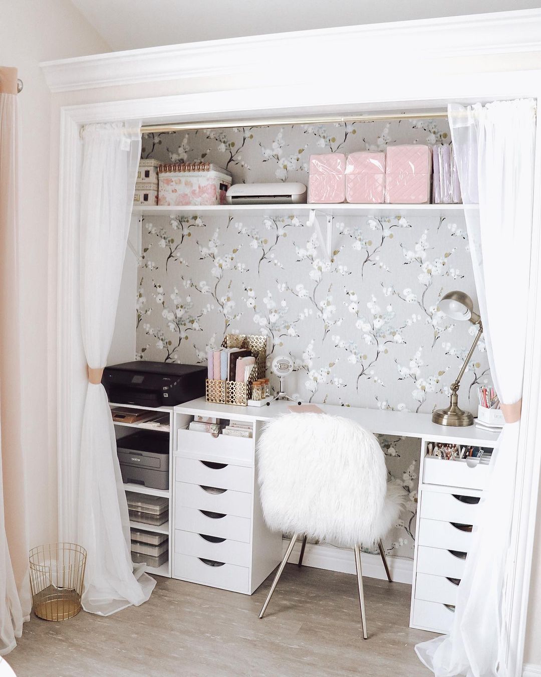 A cloffice with flowery wallpaper and white curtains