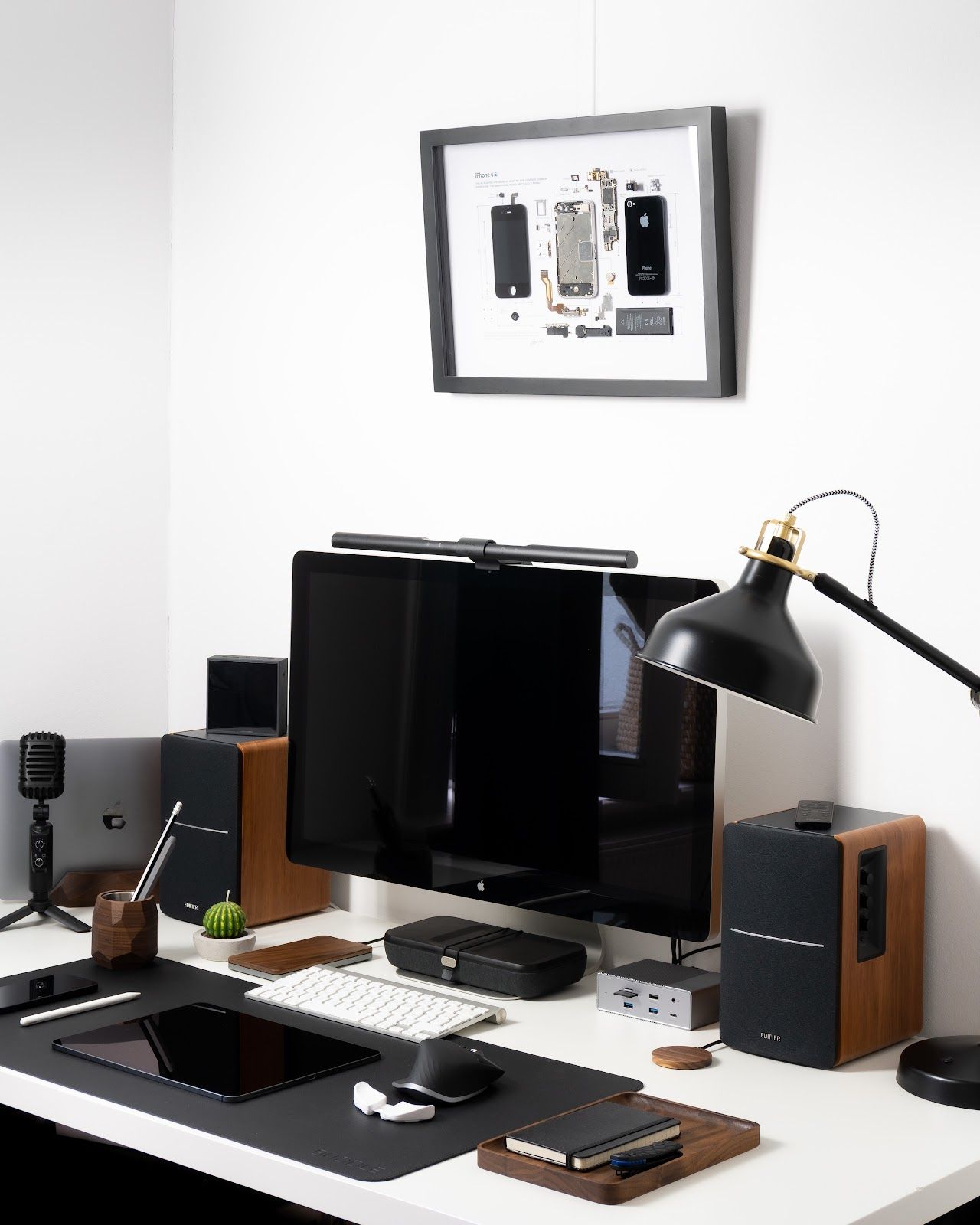 The artwork above the desk is made from disassembled Apple parts. One is an iPhone 4S, and the other is the first Apple Watch. Both are made by Gridstudio