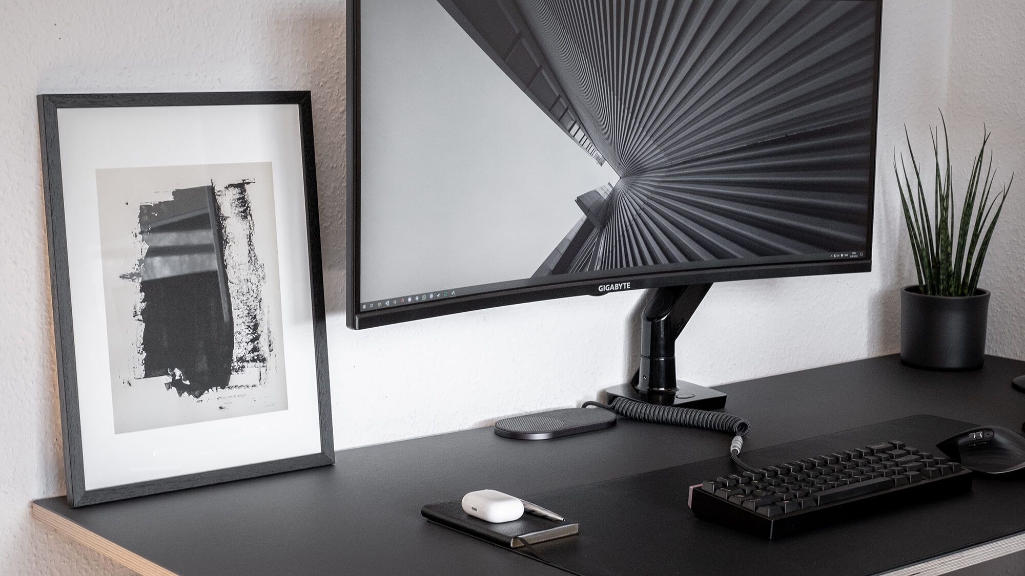 Black and white monochrome desk setup with a plant and an art print
