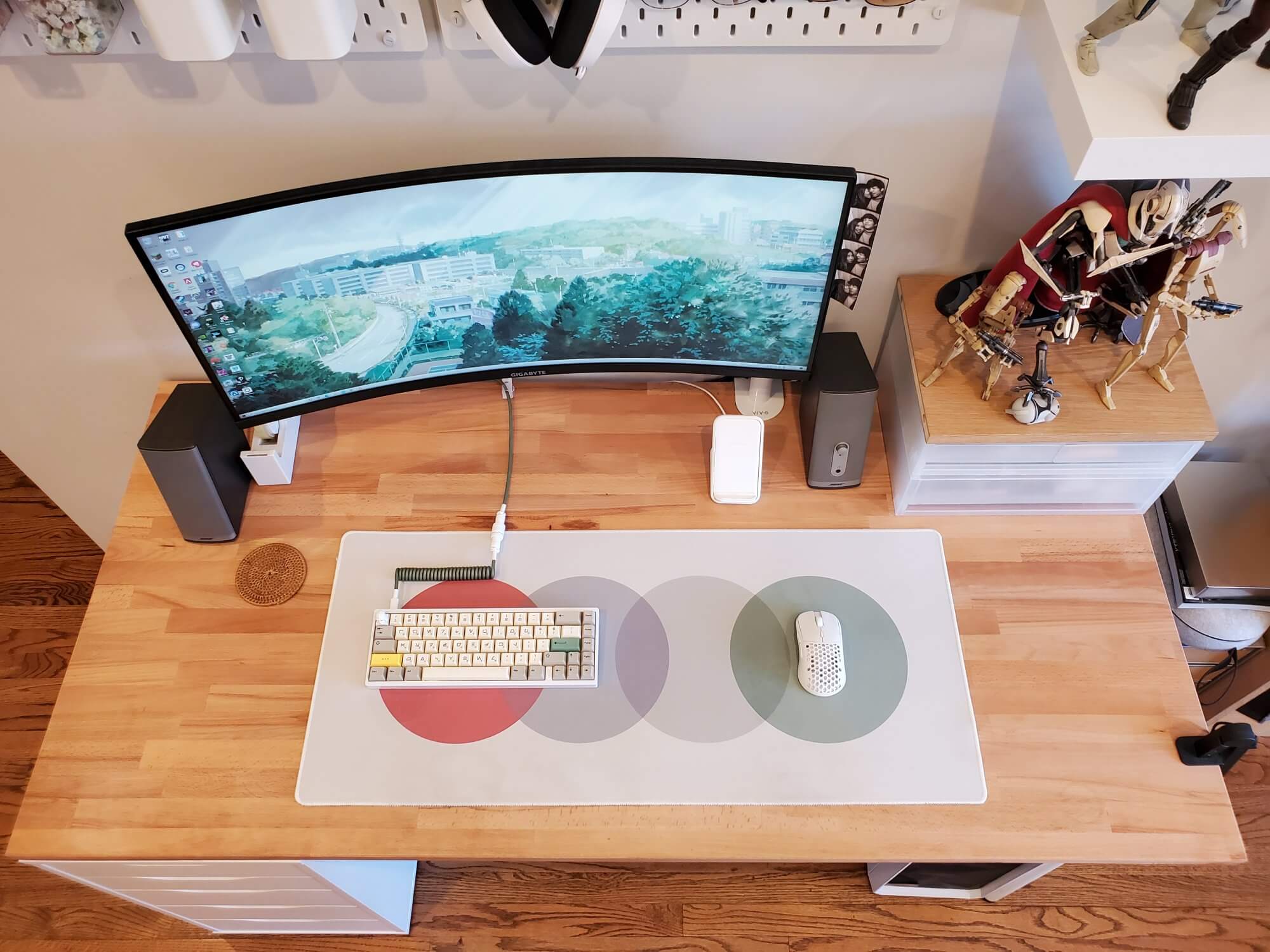 A desk setup featuring an ultrawide monitor, custom mechanical keyboard, desk pad, and a mouse