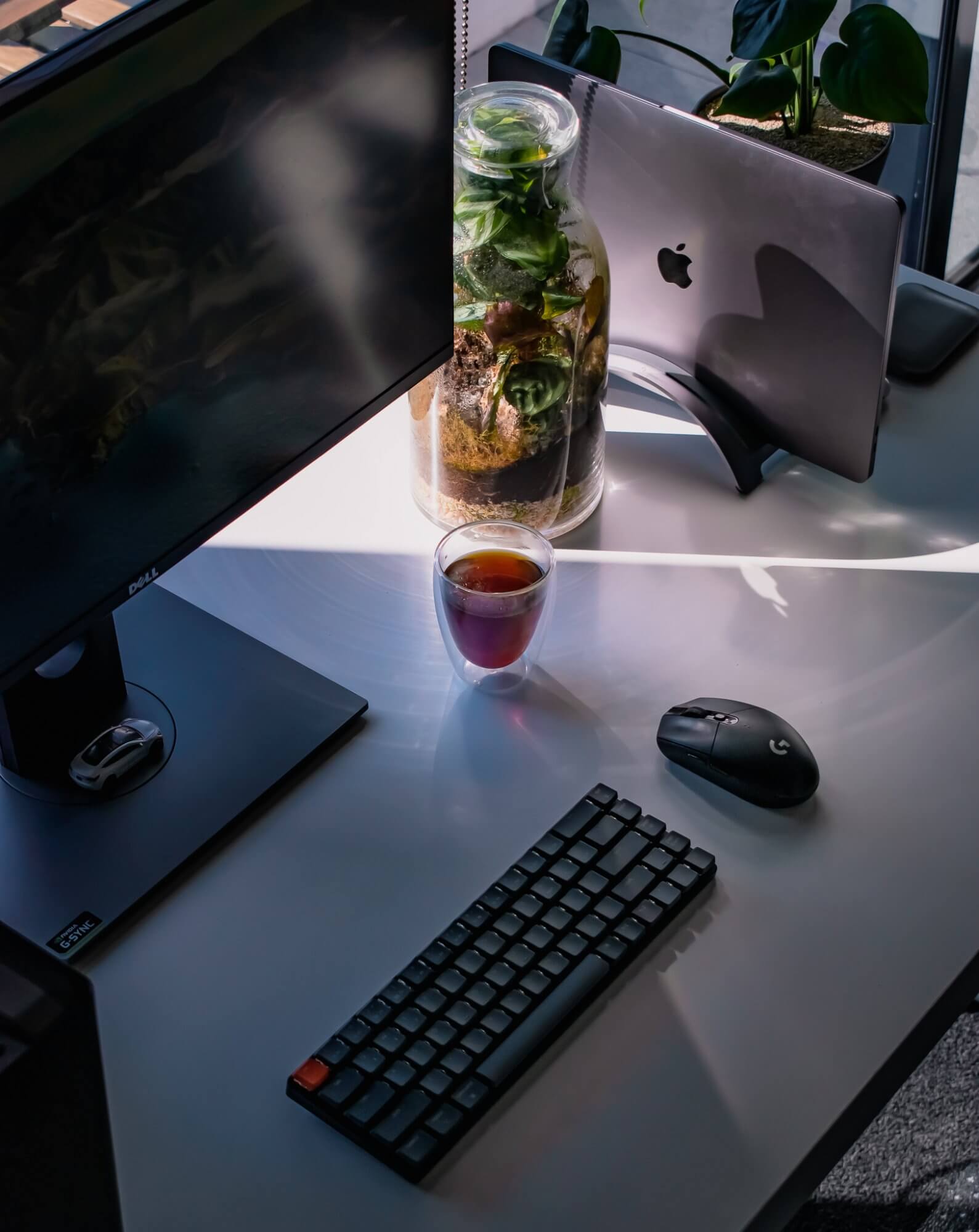 A minimalist desk setup with a Keychron keyboard, a Logitech mouse and a cup of coffee