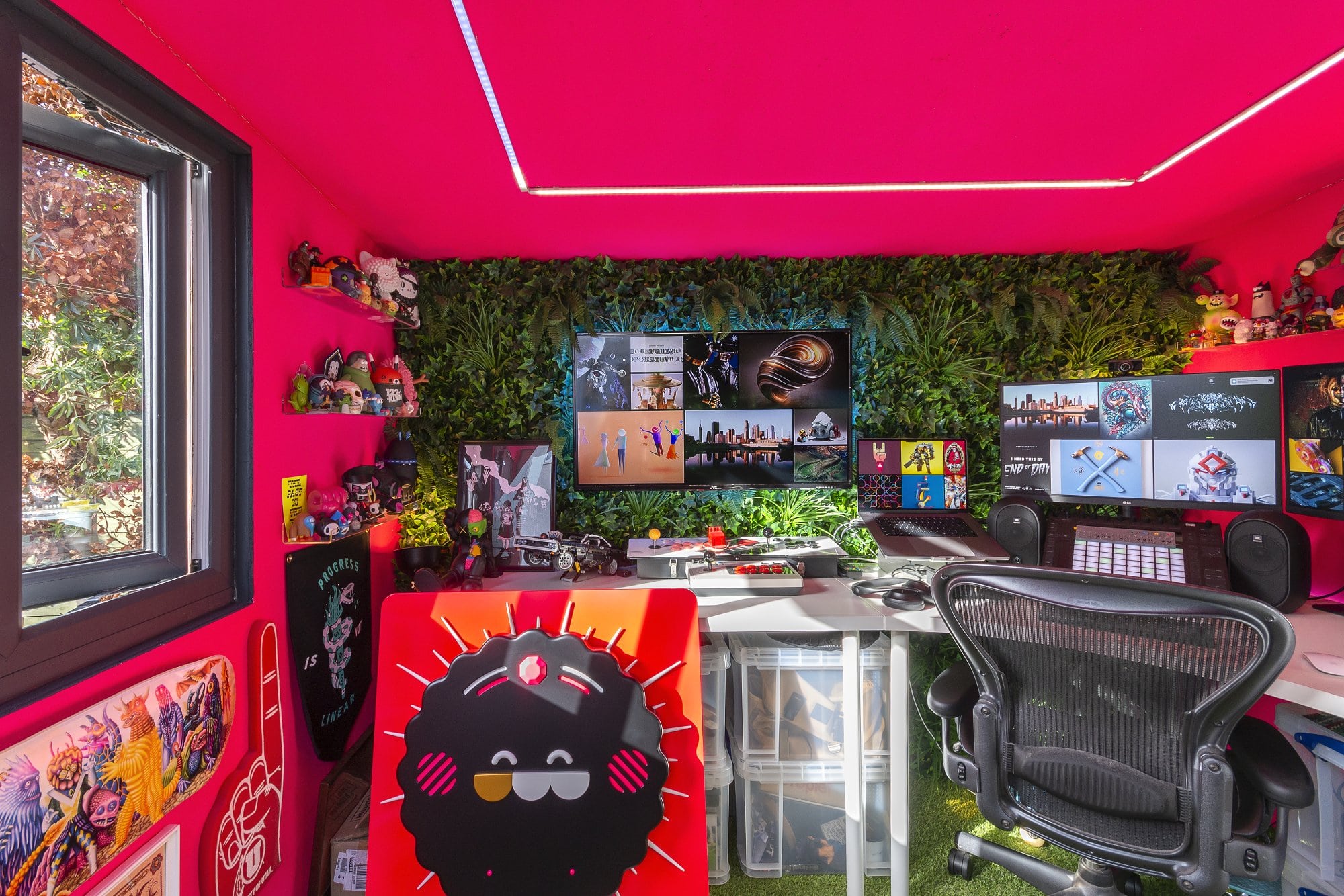 A neon pink desk setup with fake plants