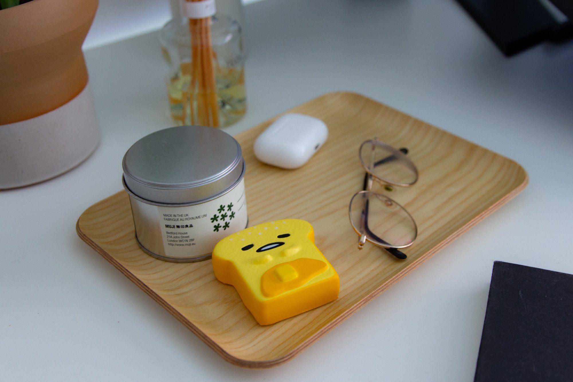 A Gudetama squishy anti-stress toy, a candle, glasses and Apple AirPods Pro