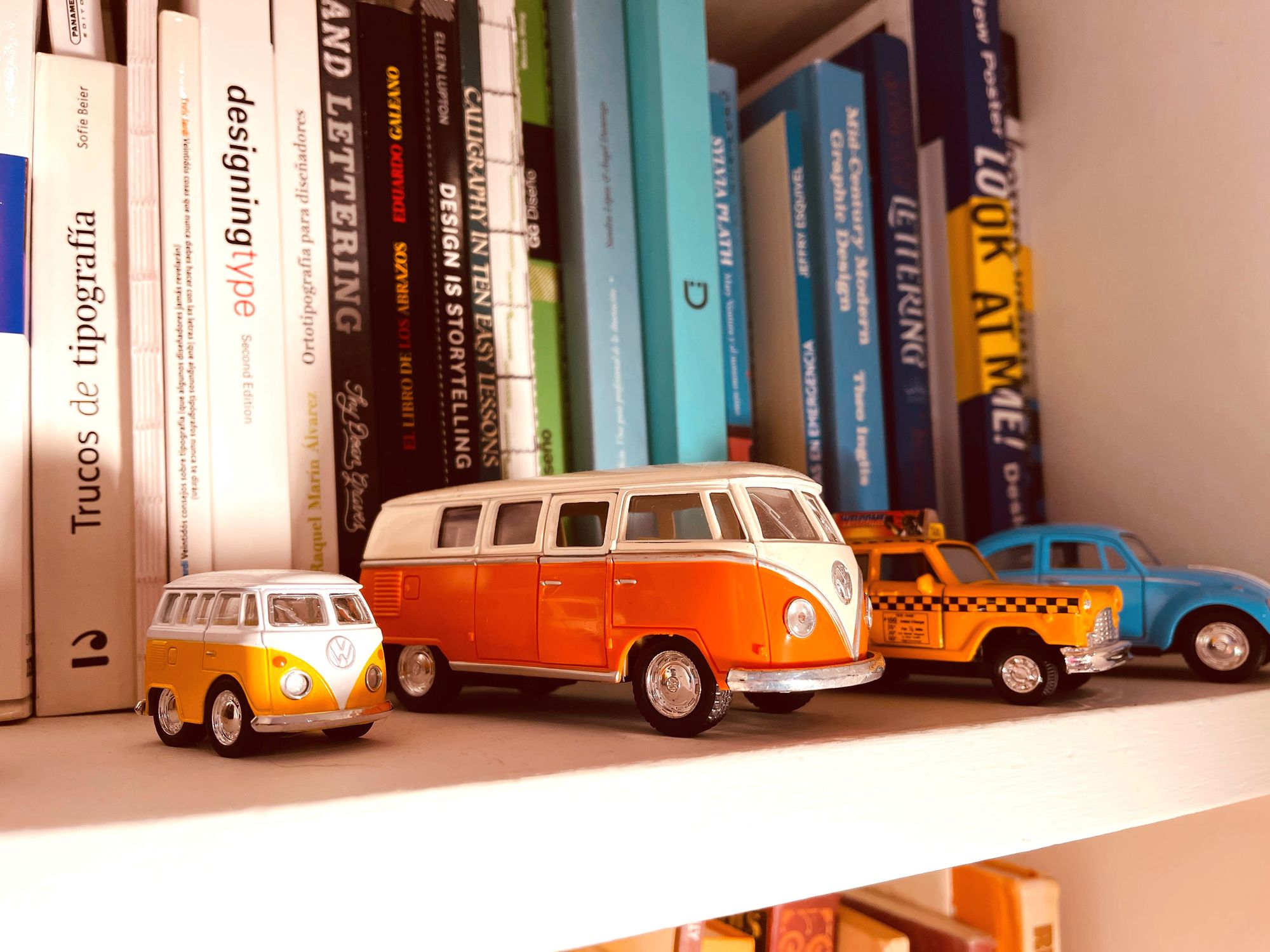 A collection of books and toy cars on a shelf