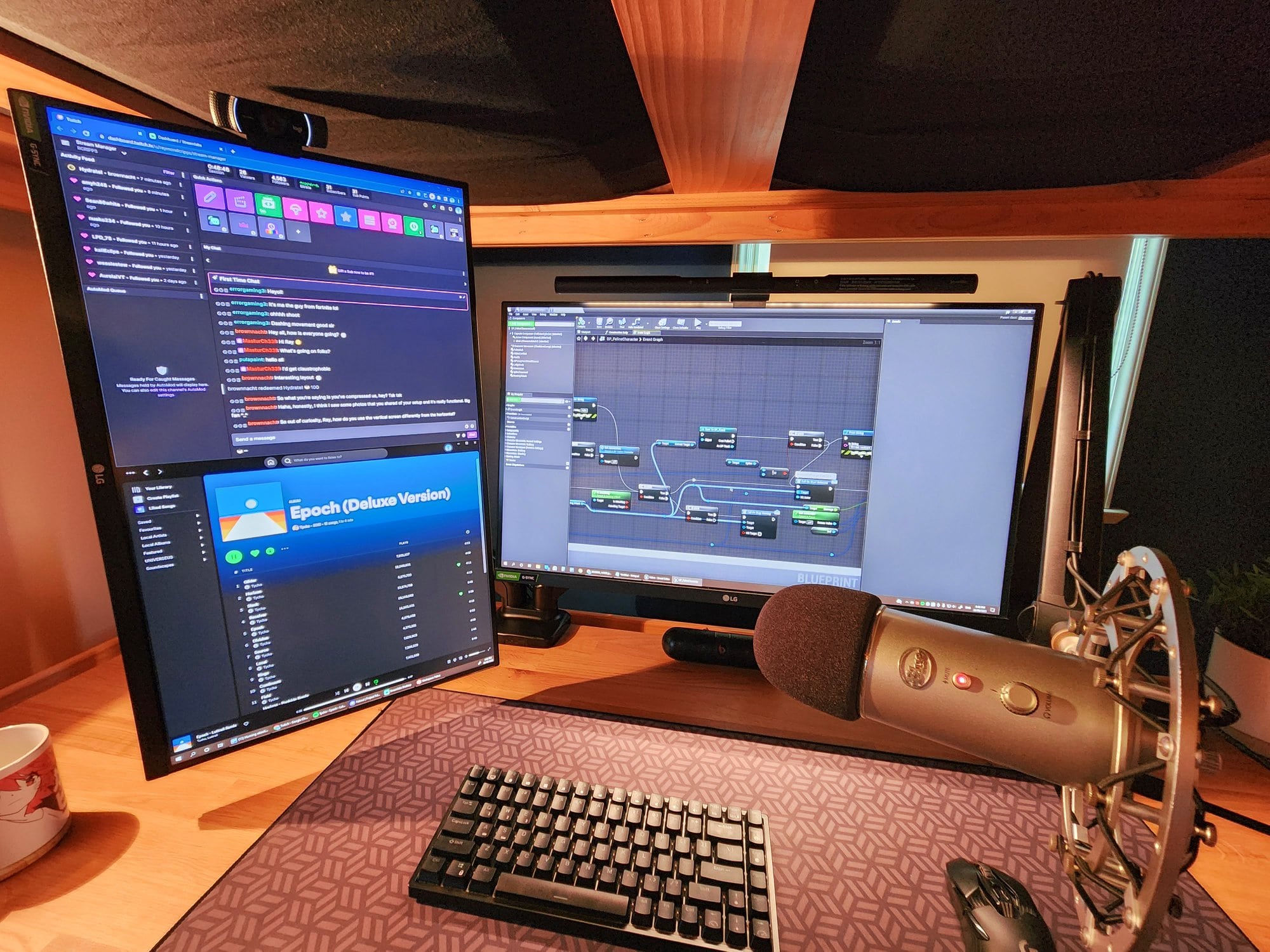 Two 27″ monitors, a microphone, a webcam, and peripherals hooked up to them at the desk setup