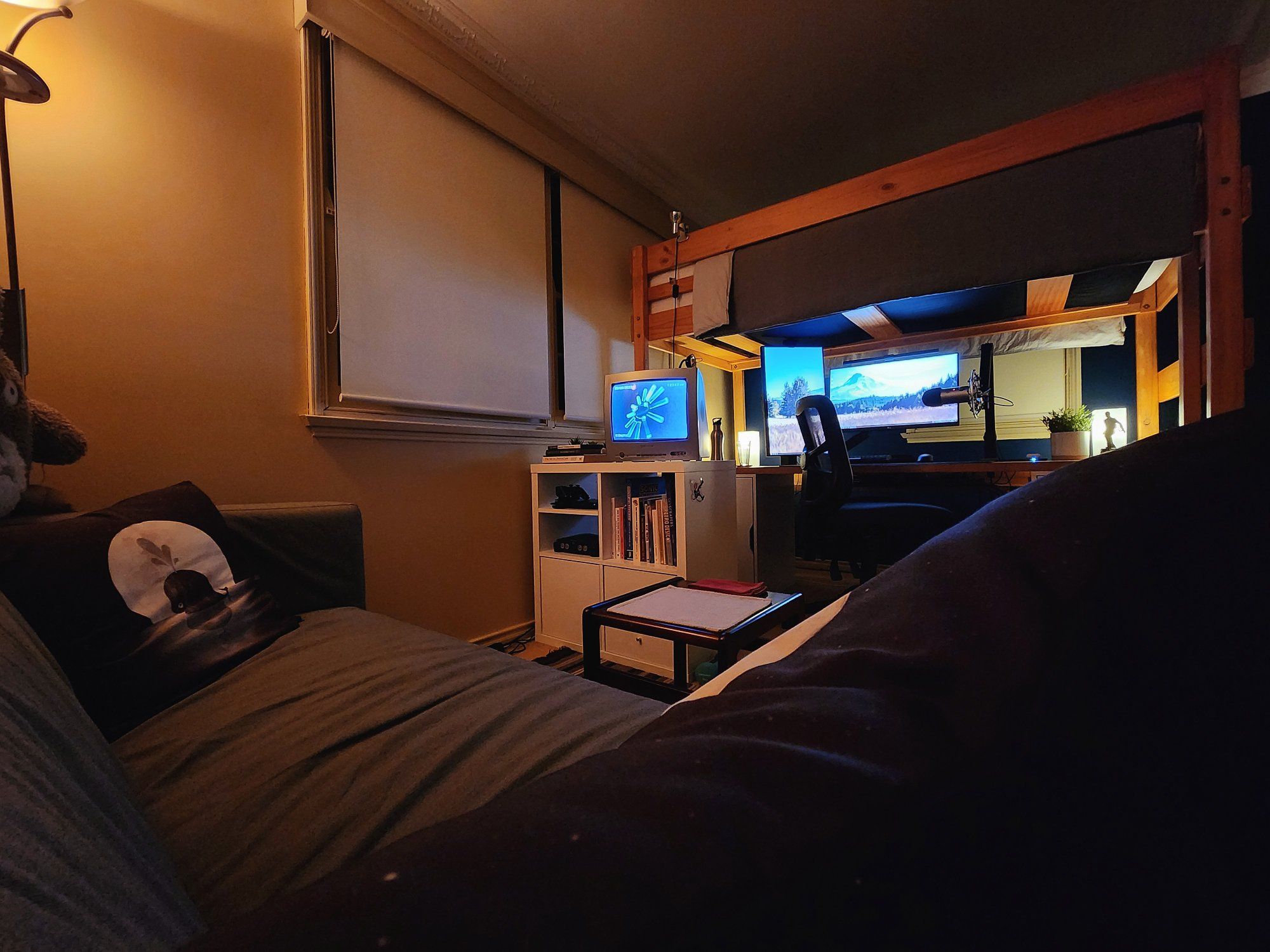 A small bedroom with a gaming desk setup under the loft bed