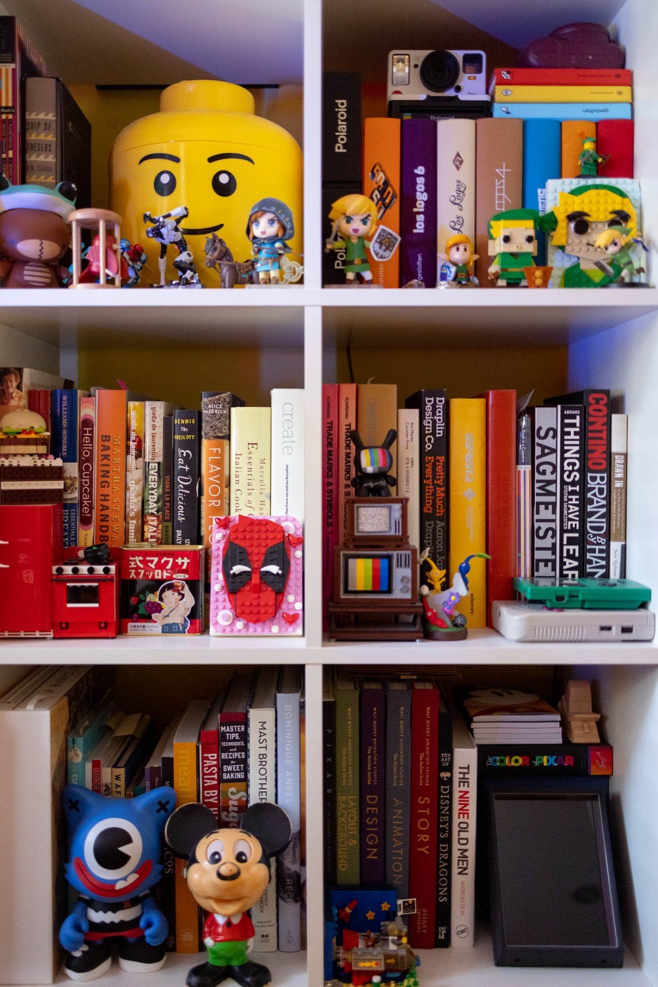 The shelf with books, toys, cameras and games
