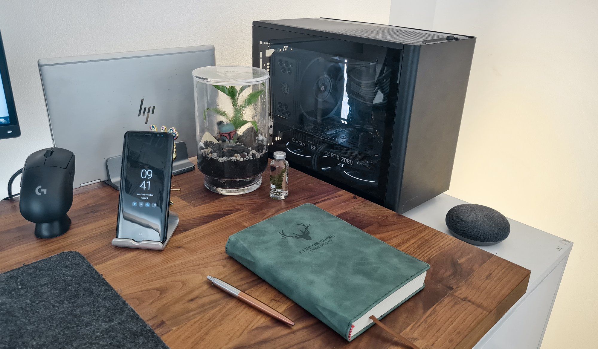 A desk setup featuring a terrarium, notebook, smartphone, laptop, GeForce RTX 2060 graphics card, and mouse