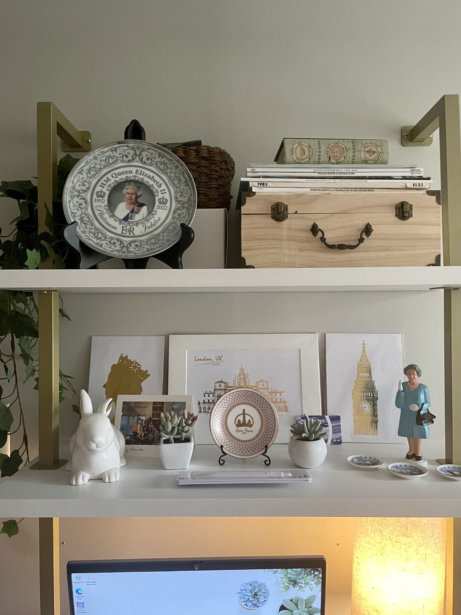 A Queen Elizabeth figurine, London postcards, and other British souvenirs on the shelves in Rochelle’s home office