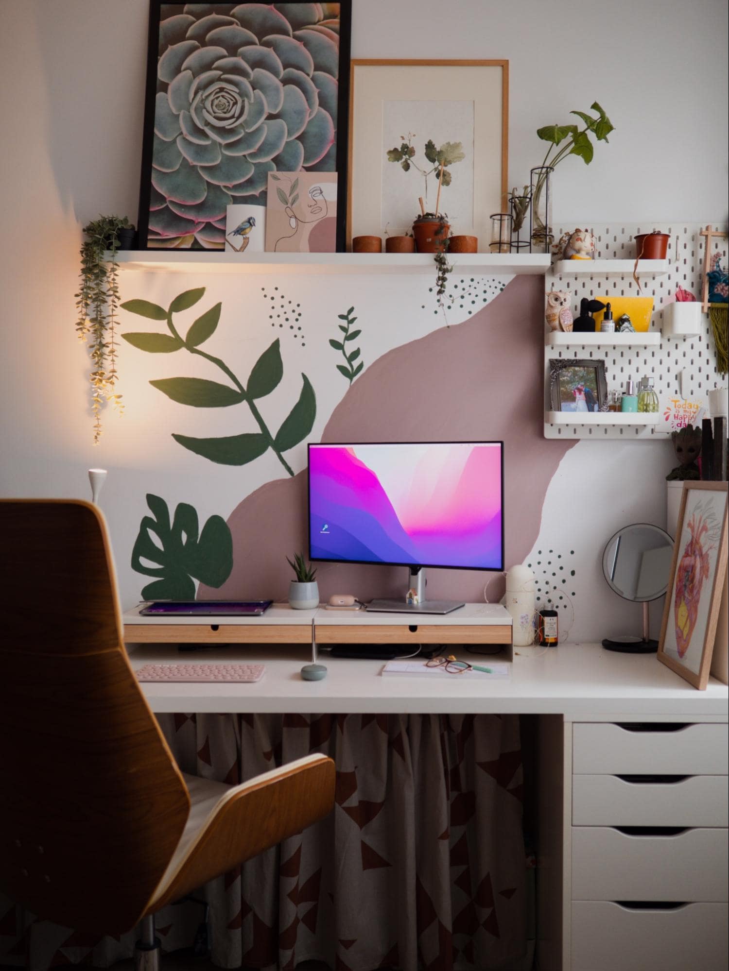 A colourful home office in Romania decorated with plants and nature-themed art, including a handmade floral motif design on the wall