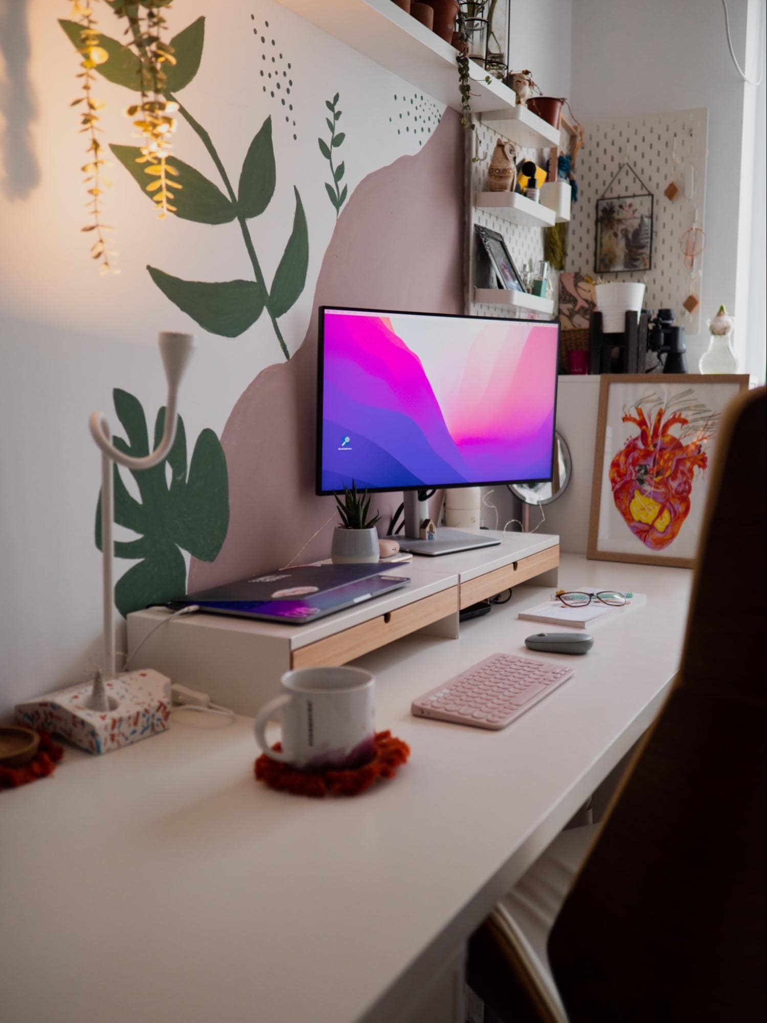 A cosy desk setup with a hand-painted wall and some artwork