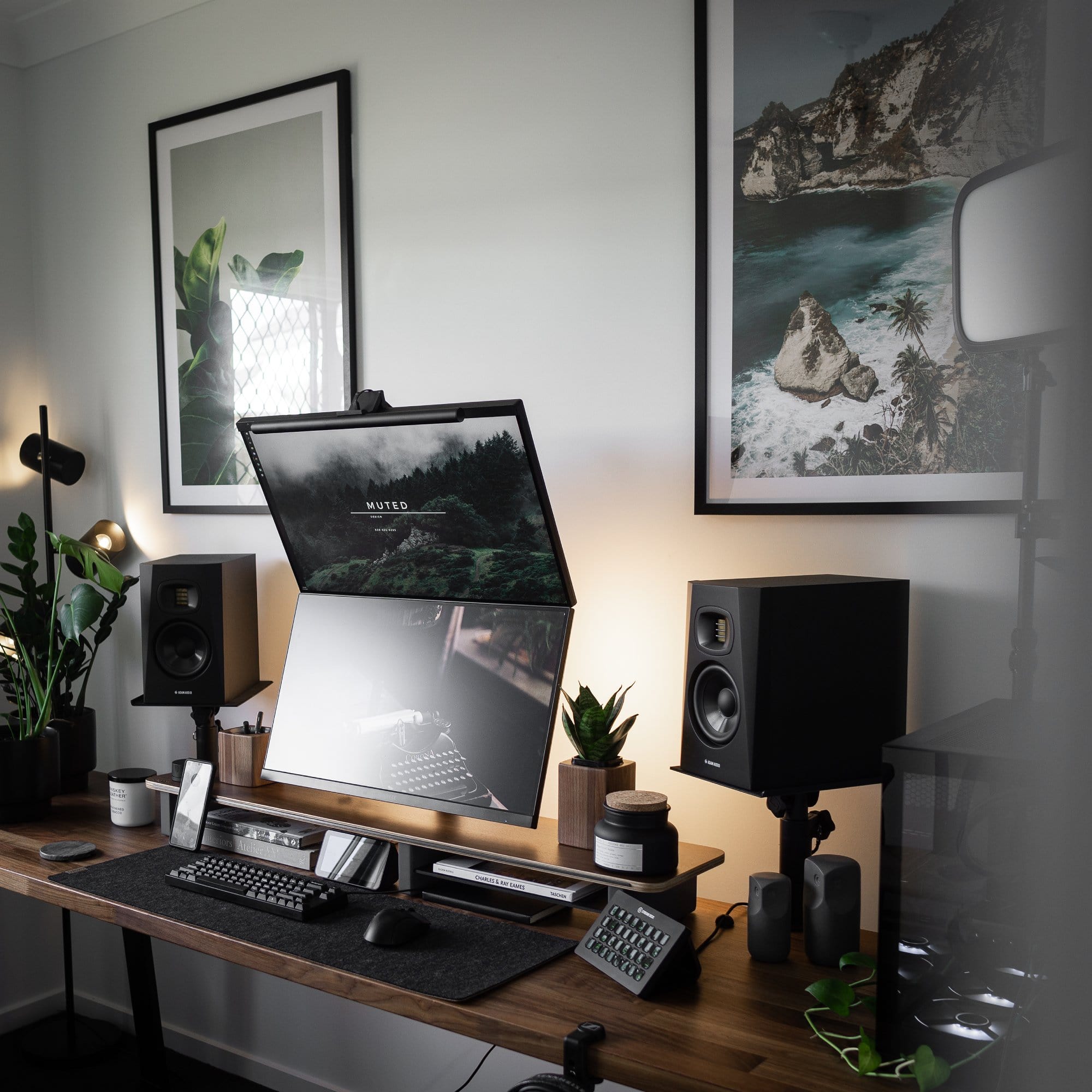 A cosy and moody dual-monitor home office with lots of greenery and nature-inspired wall art