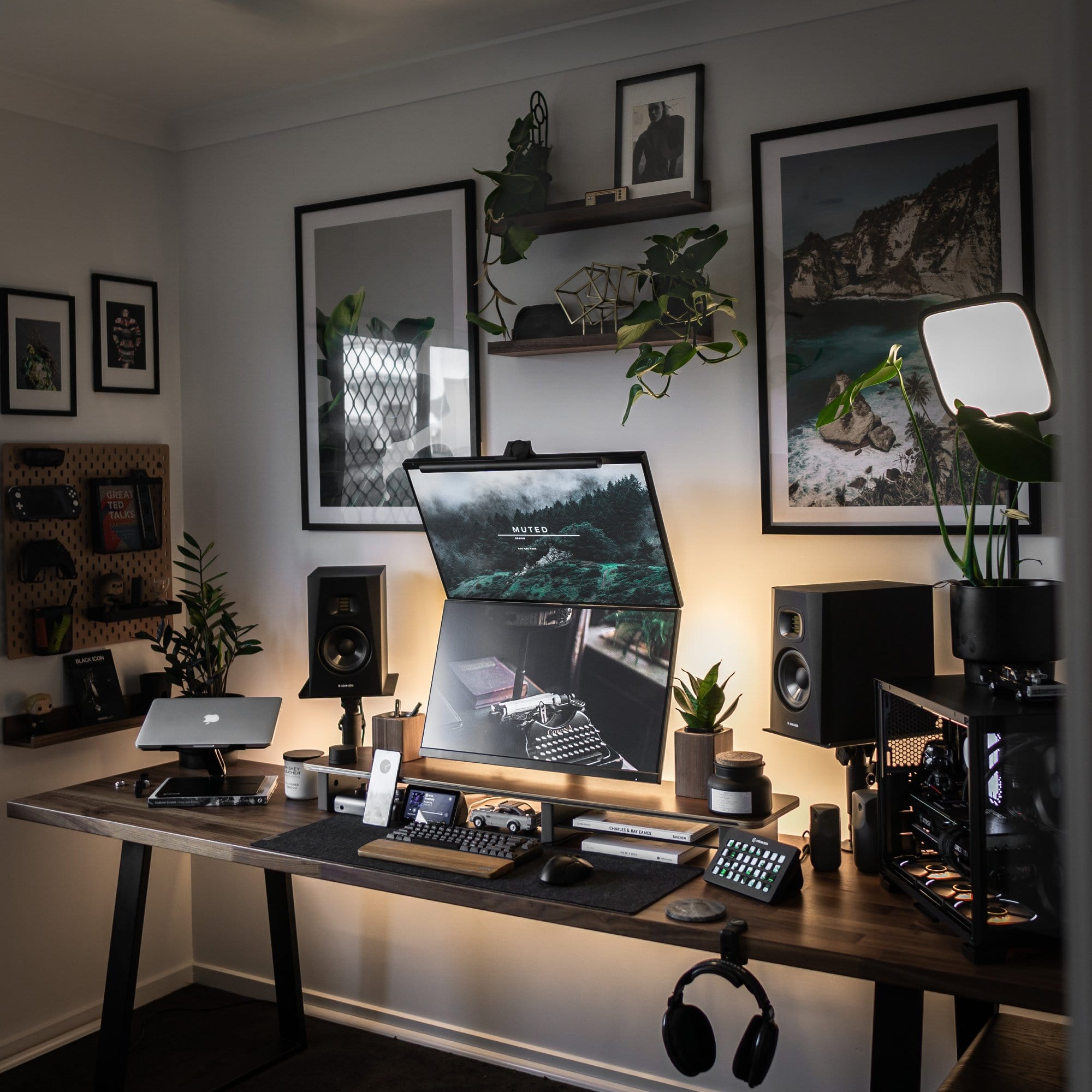 A well-organised, soothing home office setup with two monitors, some devices, peripherals, plants, photos and wall art, as well as a pegboard and shelves for more storage