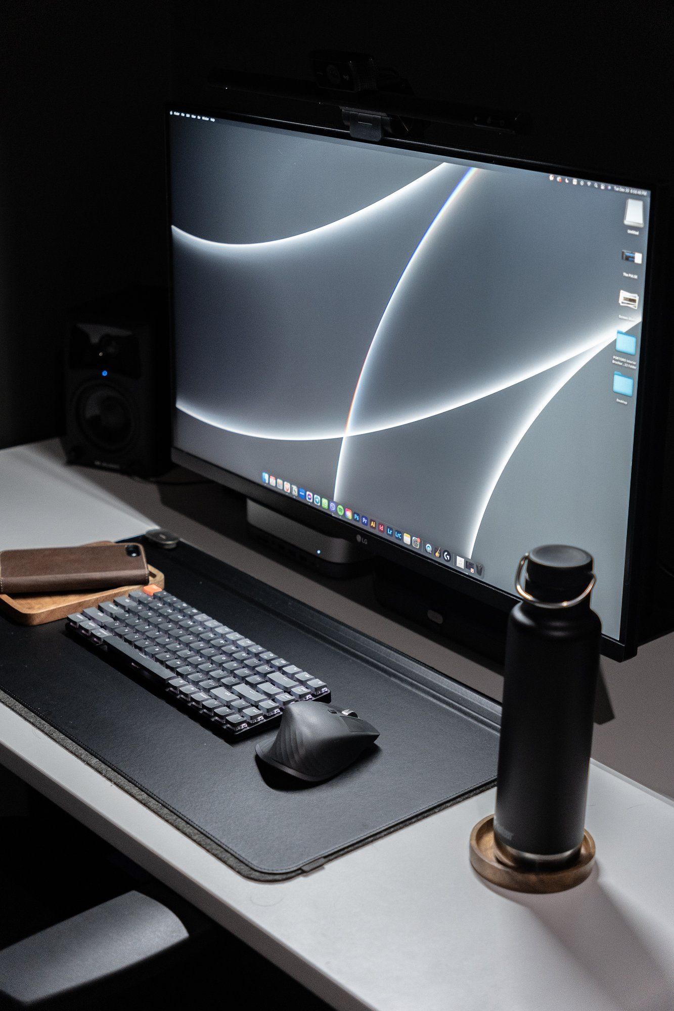 Emmie’s dark and moody home office desk setup features an LG monitor, the Keychron K3 mechanical keyboard, the Logitech MX Master 3 mouse, and a reusable water bottle