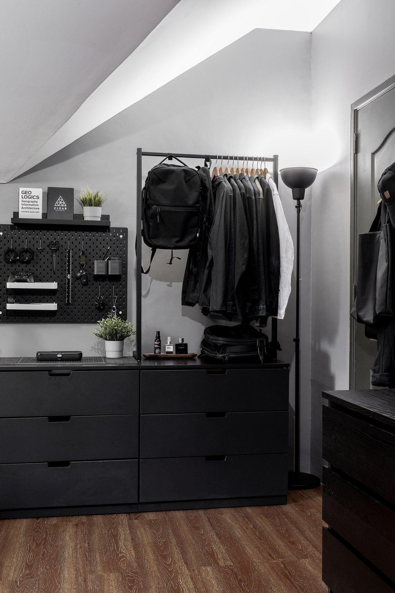 The minimal, neatly-organised home workspace with rails to hang clothes and a backpack, as well as a metal pegboard on the wall