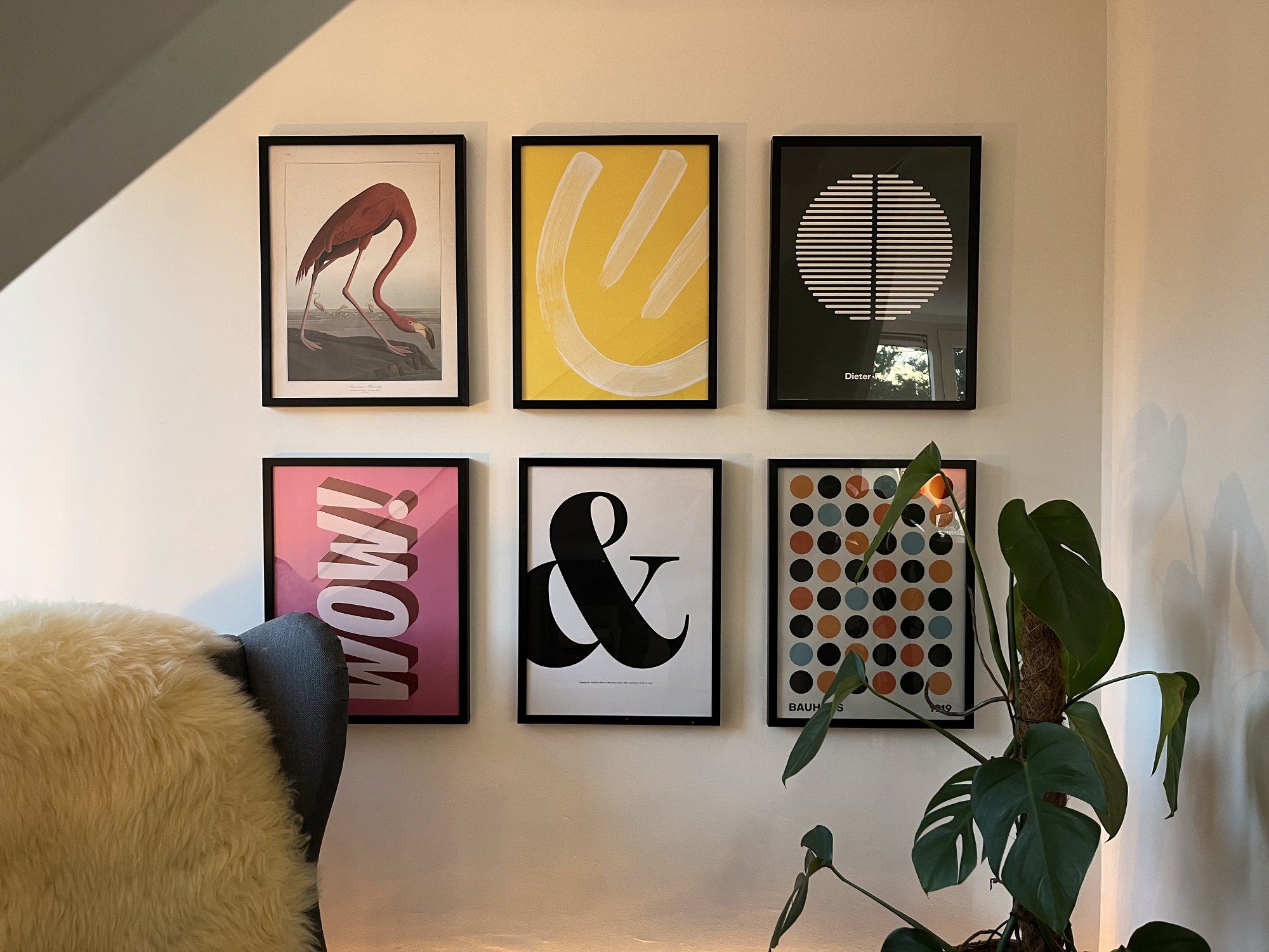 Art posters on the wall with an IKEA armchair and the Monstera plant in the foreground