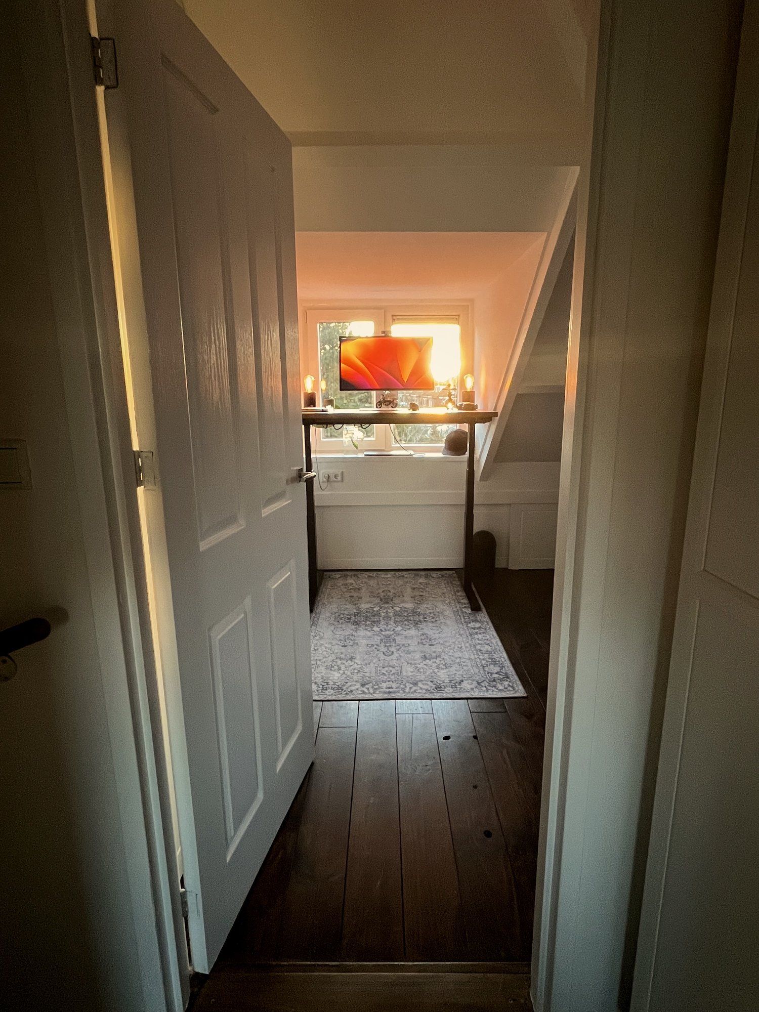 A standing desk setup near the window in the attic