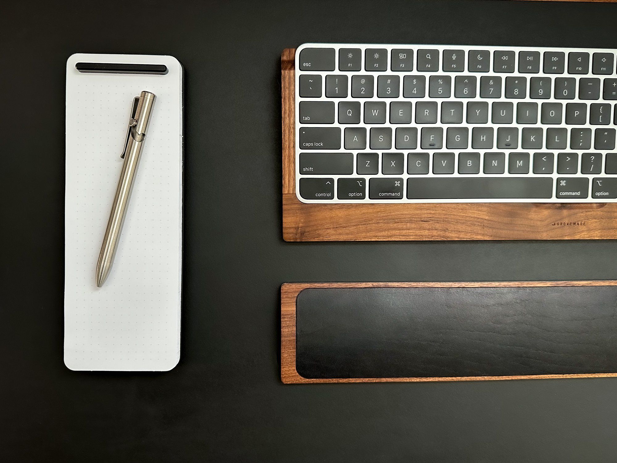 A Grovemade’s refillable notepad with a Tactile Turn Bolt Action Pen, an Apple Touch ID keyboard, and a Grovemade keyboard wrist rest