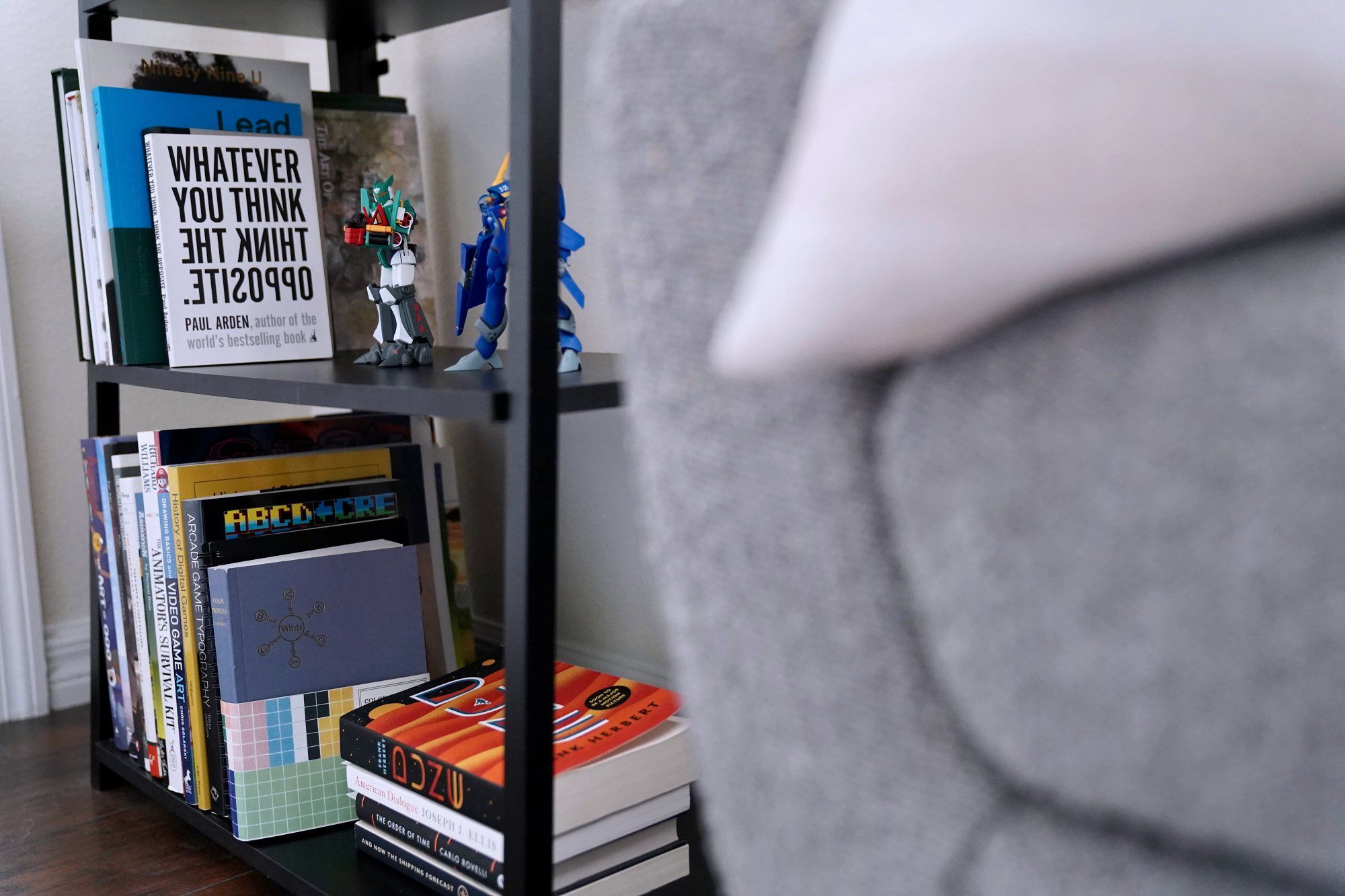 Books and action figures on the shelves of a free-standing bookcase