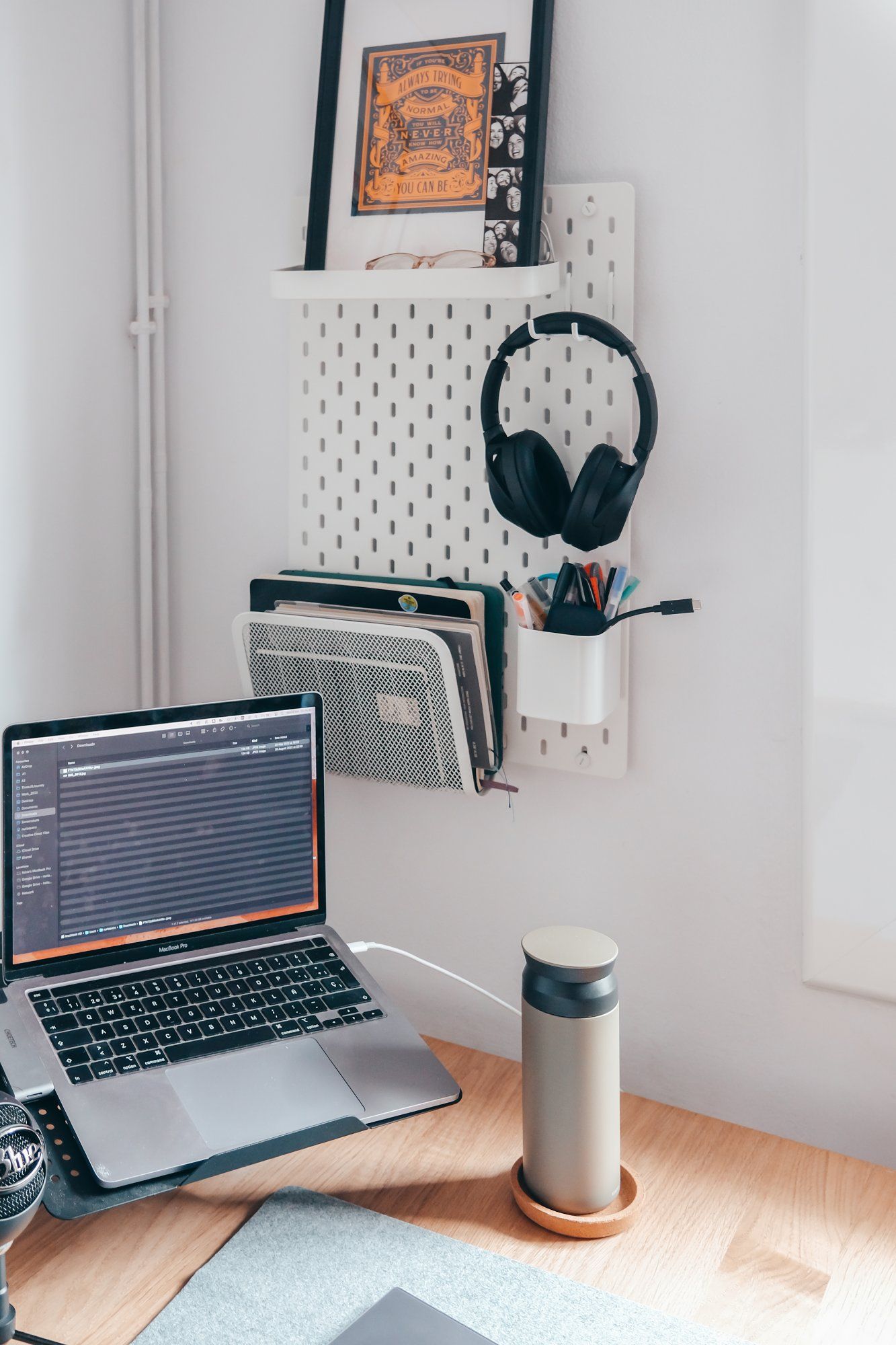 A laptop, a water bottle, and a pegboard in a home office