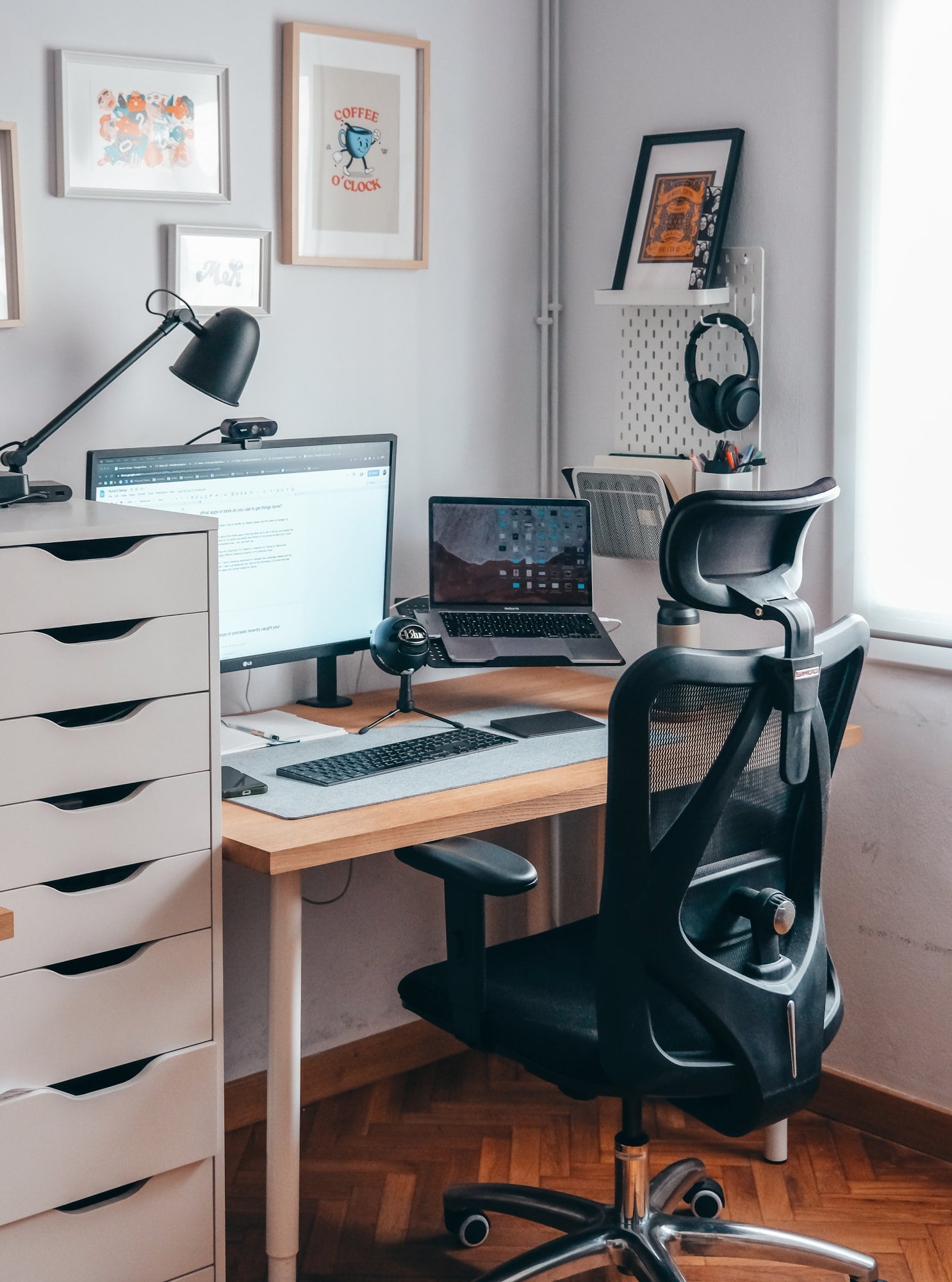 A minimal designer home office setup featuring a desk with a monitor and a laptop, an office chair, and an ALEX drawer