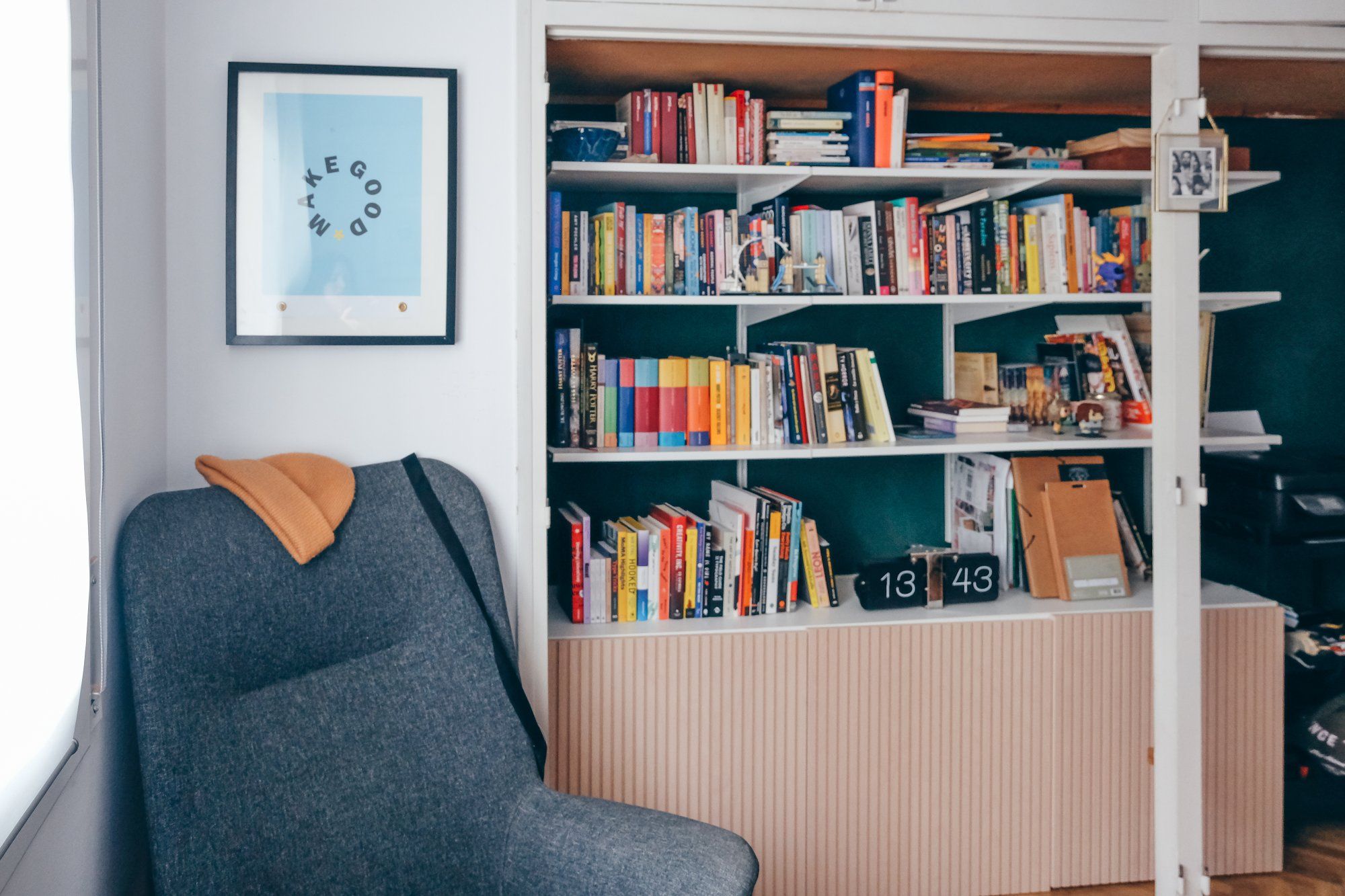 A collection of books on the shelves, an armchair, and a Make Good poster hanging on the home office’s wall