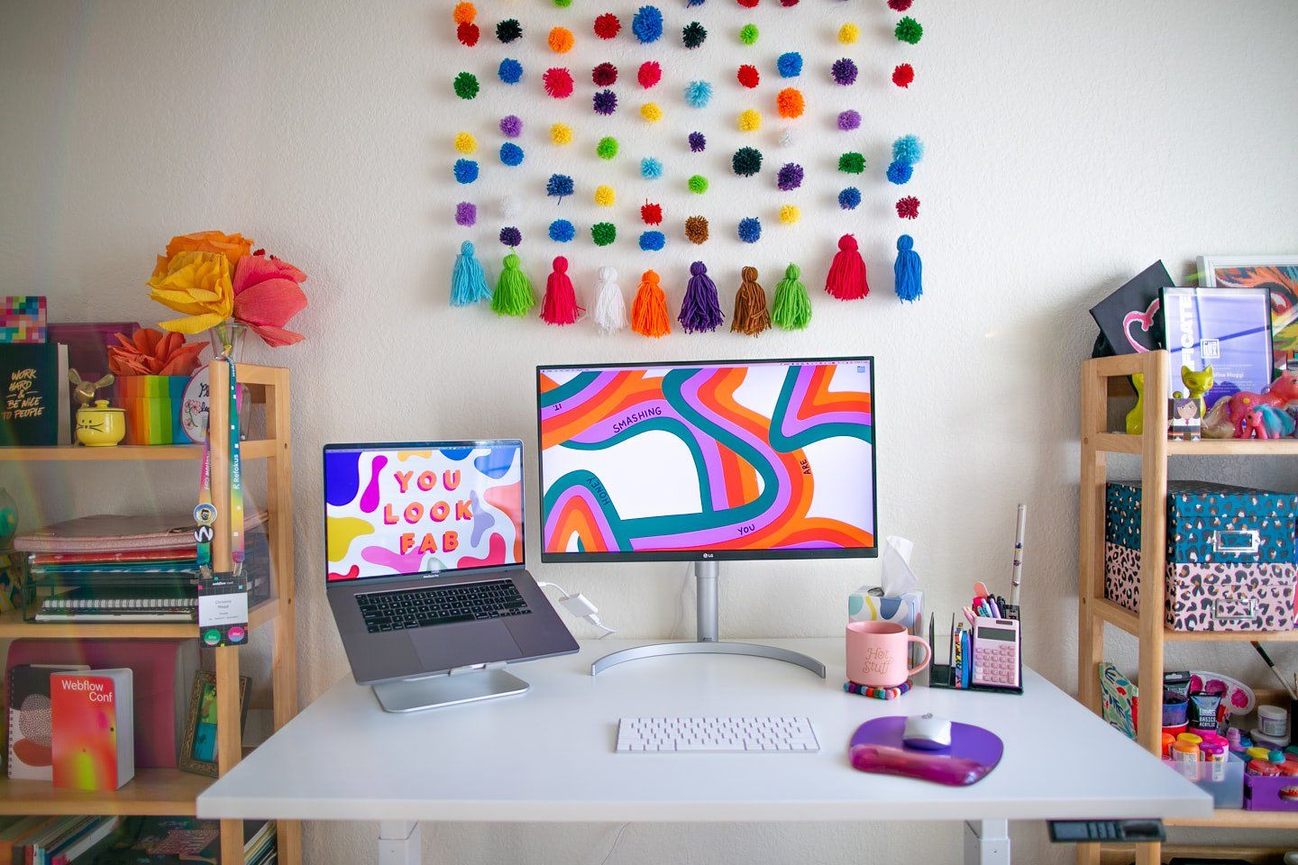 A colourful desk setup with an LG Ultrafine monitor, a MacBook Pro laptop, an Apple Magic keyboard, and a Logitech MX 3 mouse