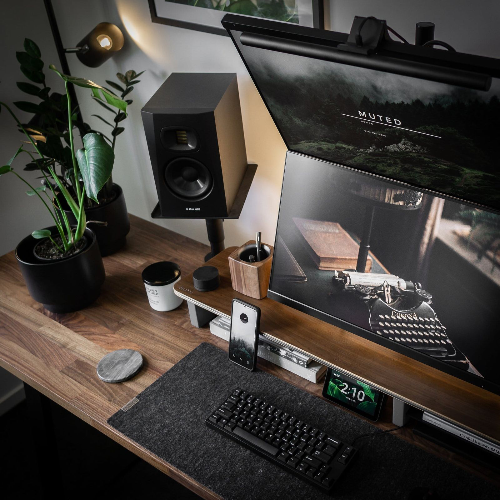 The moody workspace with vertically stacked monitors and two plants in dark pots