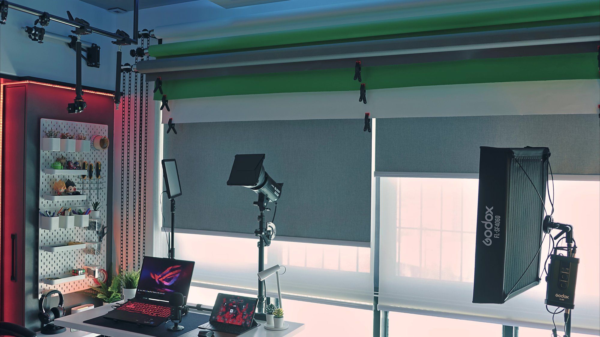 A corner of Ron Tek’s home office setup, featuring three seamless paper roll backdrops positioned above the window, along with some gear and devices for video shooting