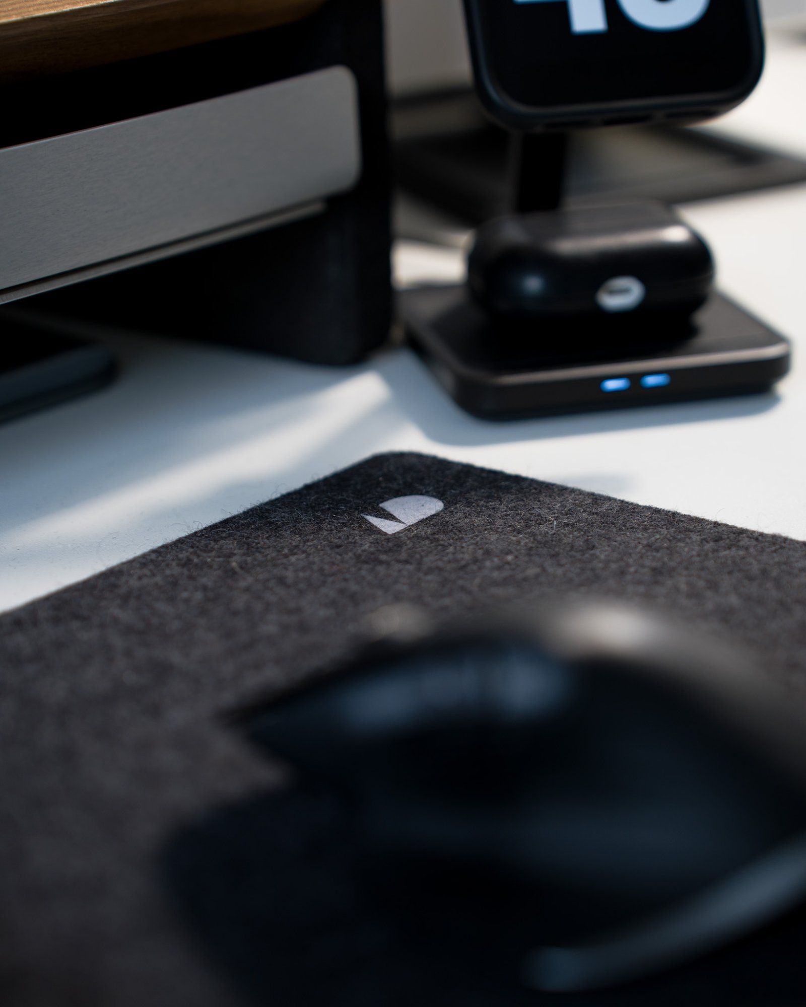 A close-up of an Oakywood Antracite desk pad and a QuadLock dual charger for iPhone on the desk