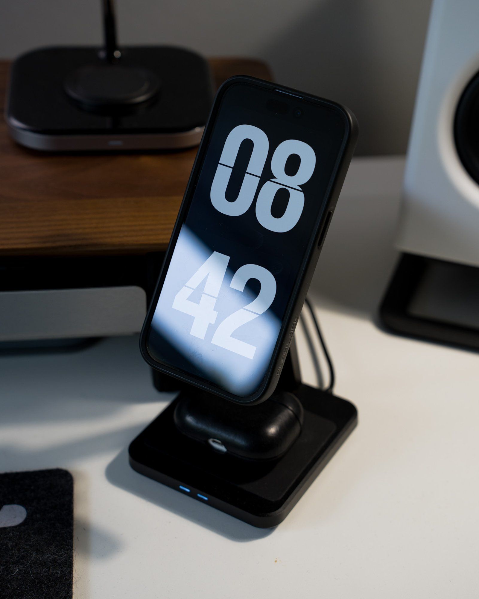 An iPhone and AirPods on a QuadLock MAG dual desktop wireless charger