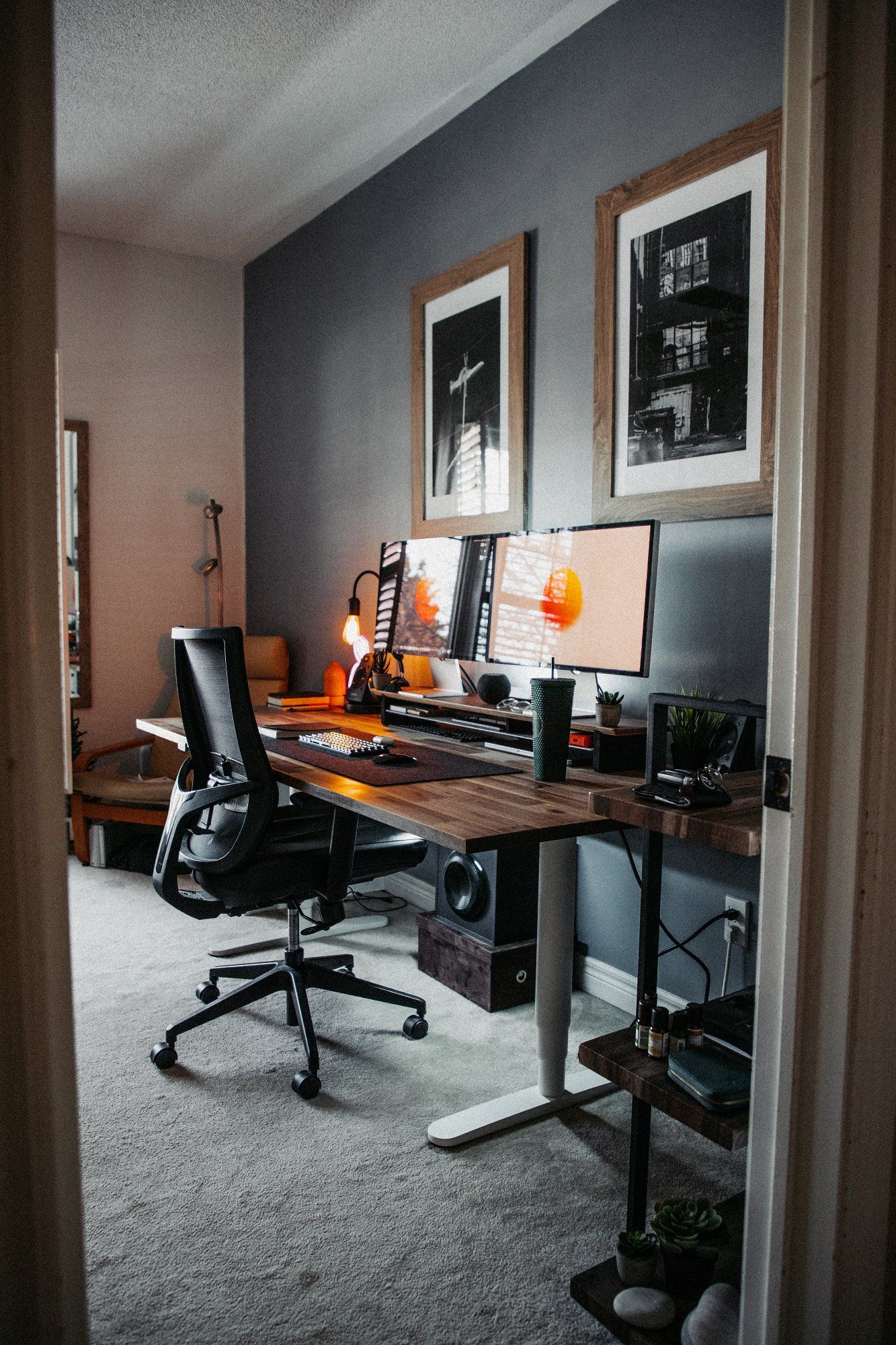 A view from the entry door of a creative standing desk workspace with two monitors
