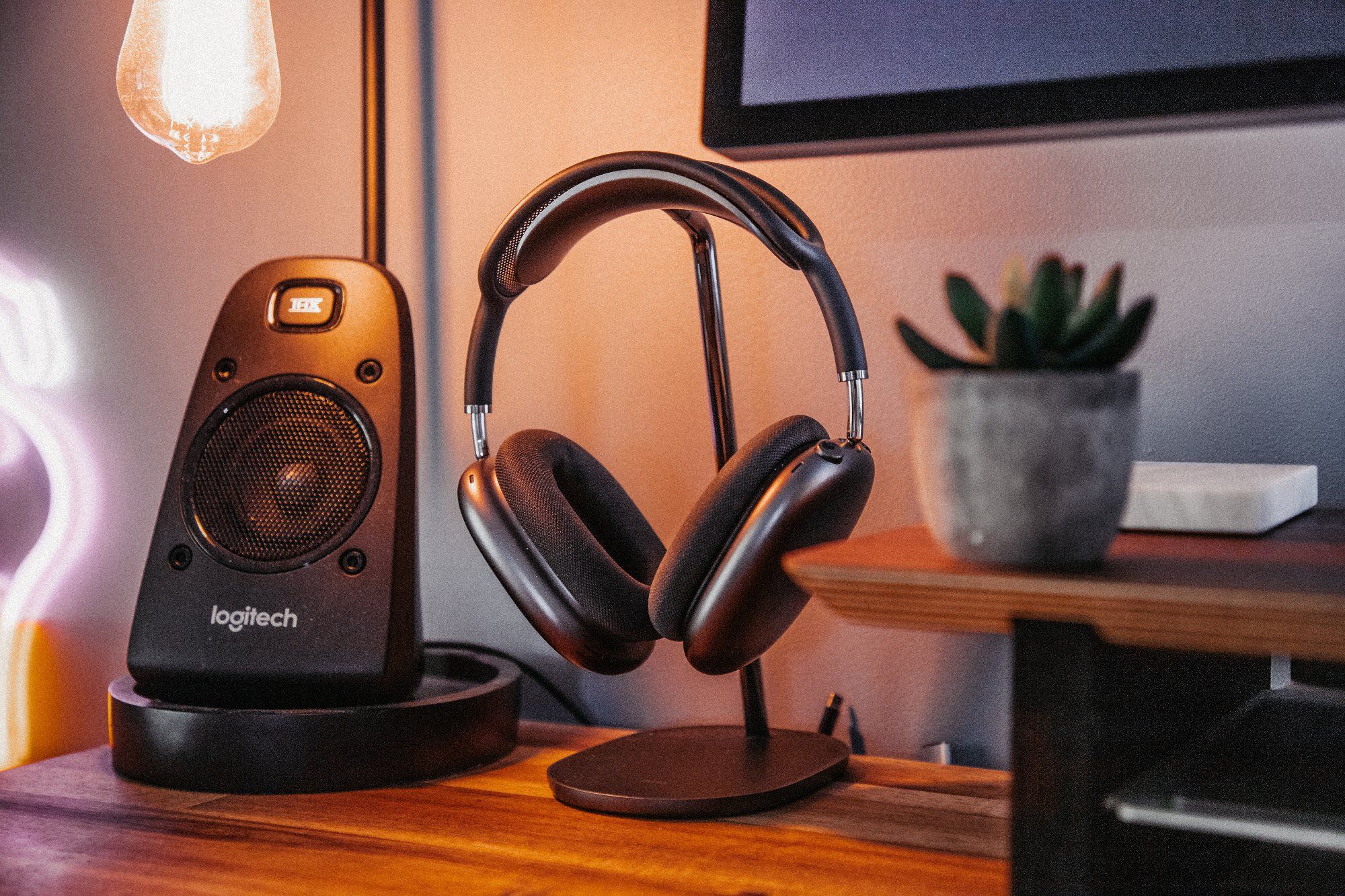 A Logitech Z623 THX speaker, AirPods Max noise-cancelling headphones, and a cactus in a small planter at the neatly-organised creative desk setup