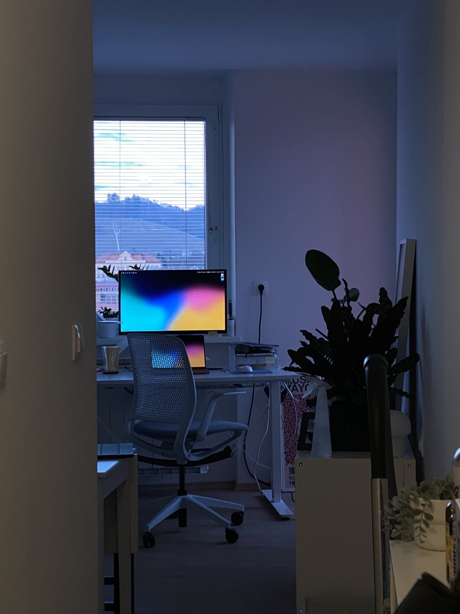A view of a bedroom home office desk setup at dusk