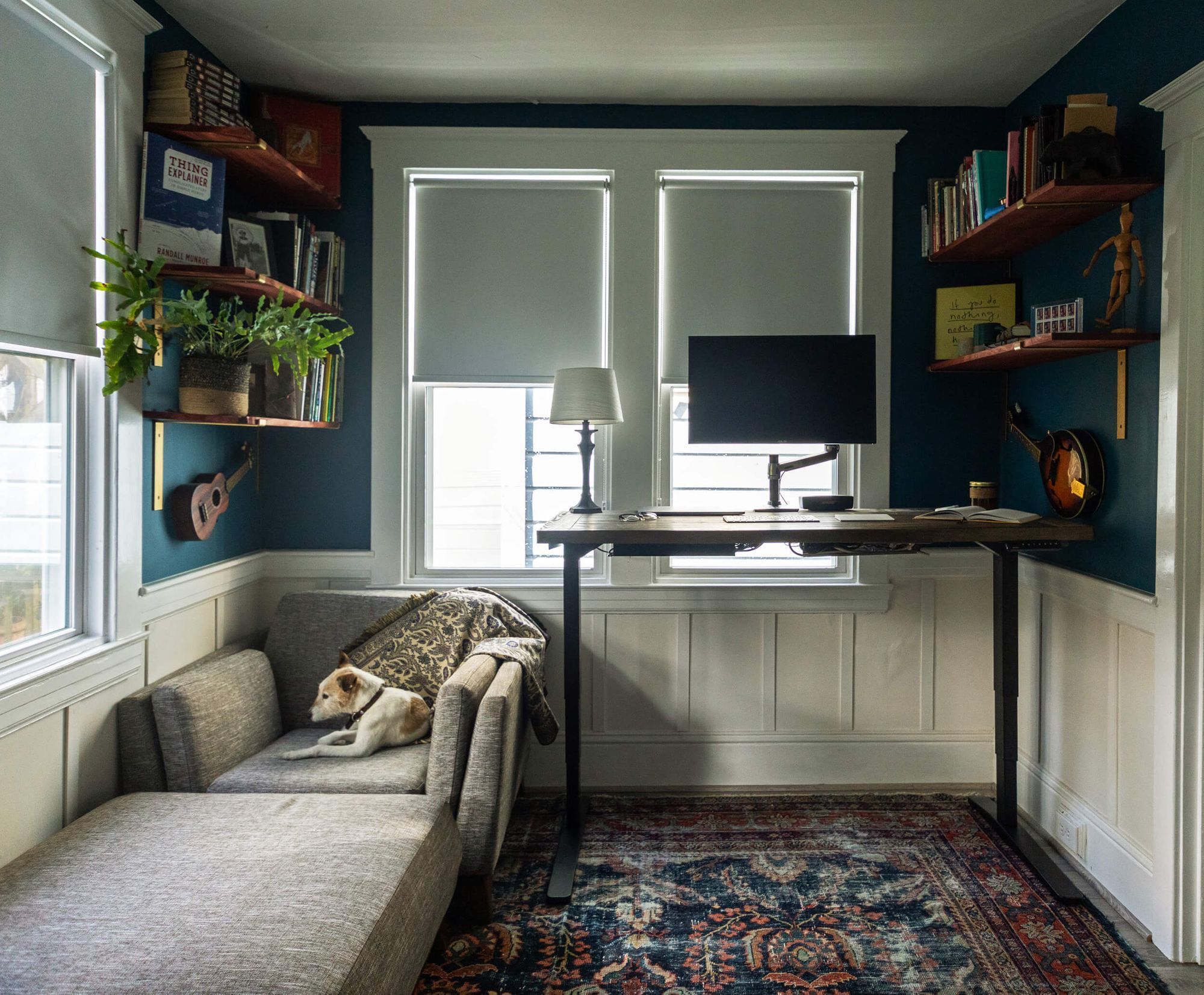 A dog chilling on a couch in a home office of their owner with a creative desk setup