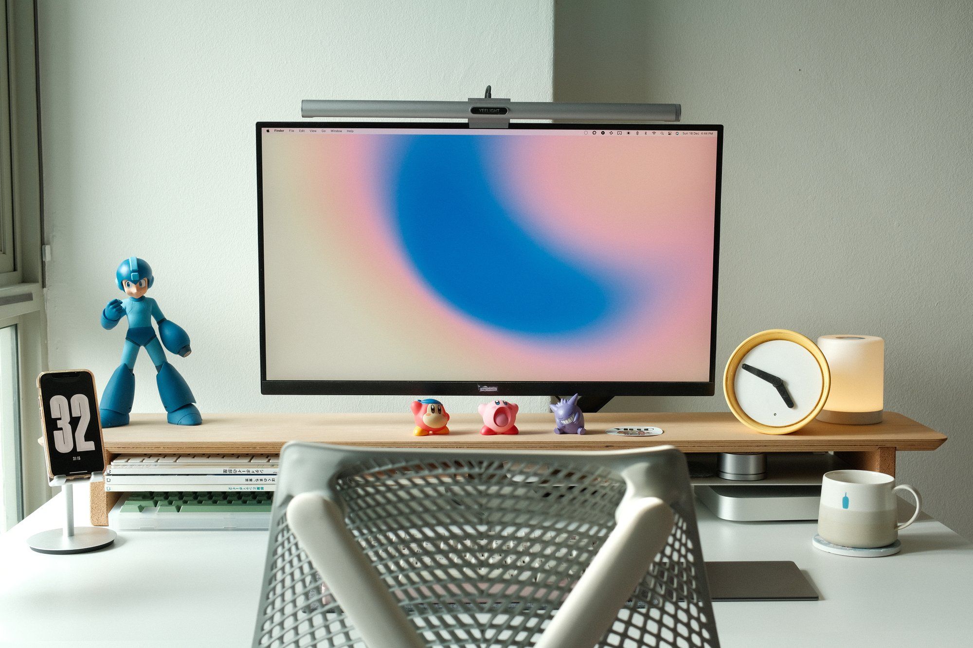 A minimal desk setup featuring an LG monitor, a Herman Miller Sayl chair, and a branded Blue Bottle coffeshop mug