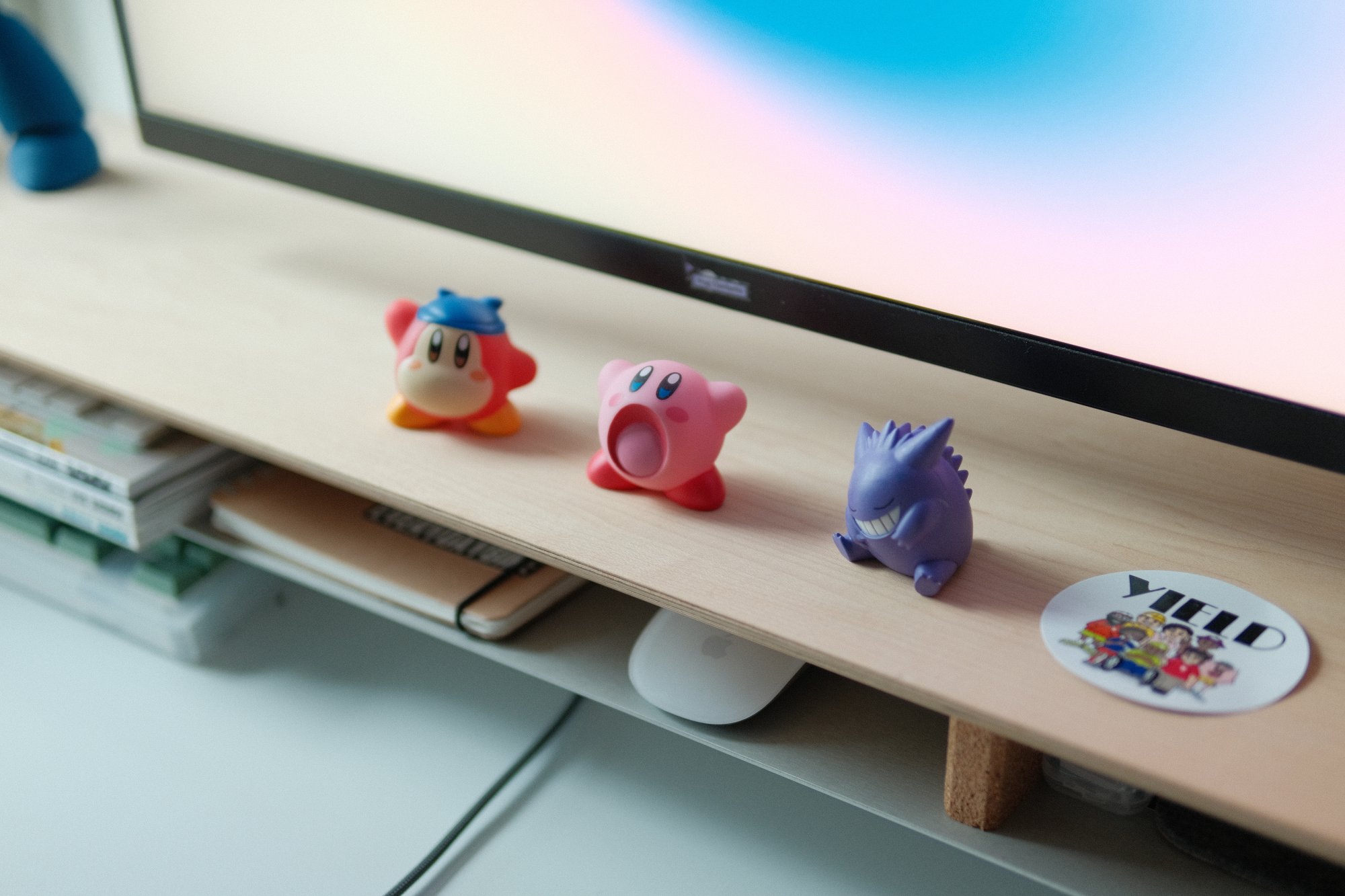 Three soft vinyl figures of characters from Nintendo's Kirby video game series are lined up on a Grovemade Maple desk shelf