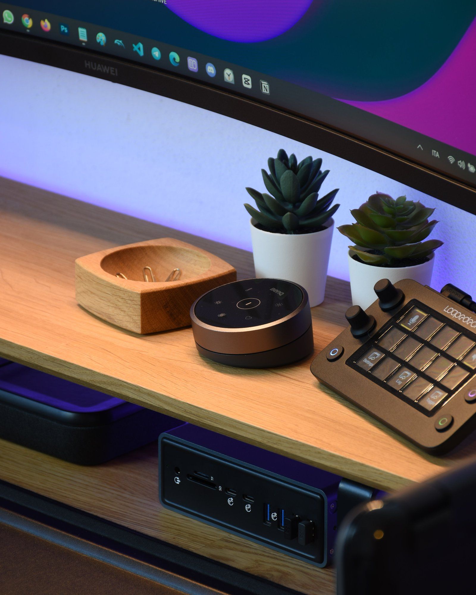 A close-up shot of a wooden desk setup with two potted succulent plants and ergonomic peripherals