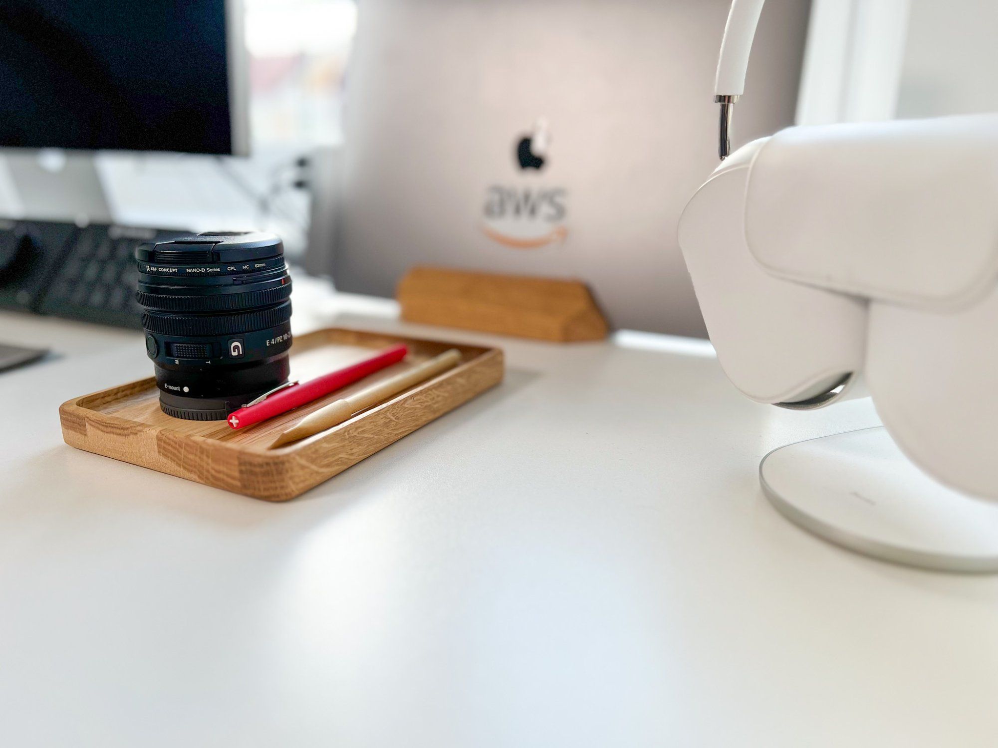 Photo of Luca Mezzalira’s desk setup, showing a stationery tray, a MacBook Pro on a stand, and the AirPods Max headphones