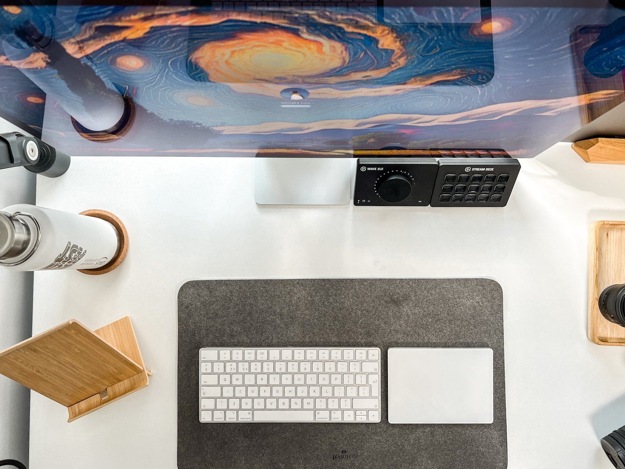 A clean and minimal Apple Studio Display desk setup shot from above