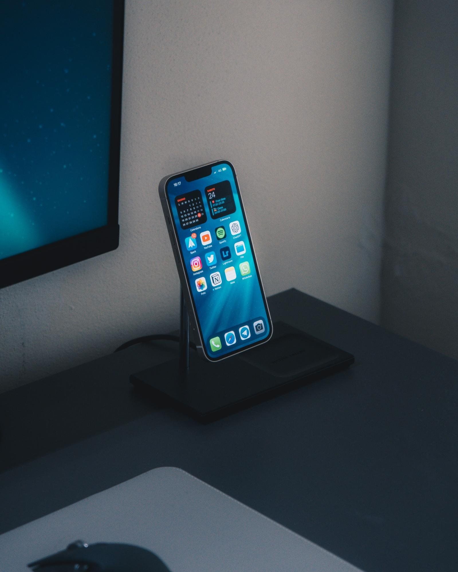 An Apple iPhone with a lit screen on a stand