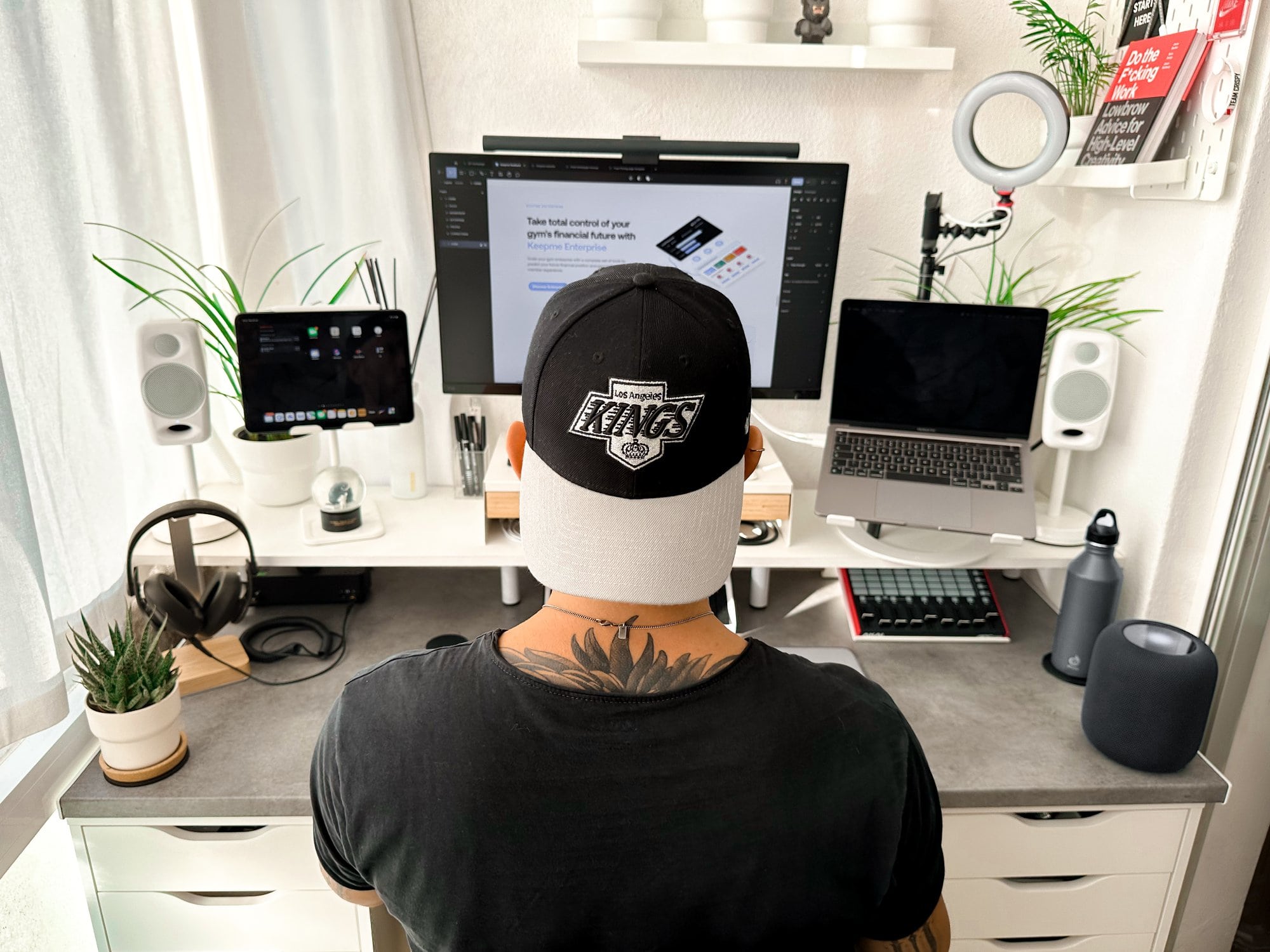 A rear view photo of Alex Napier Holland sitting at his desk