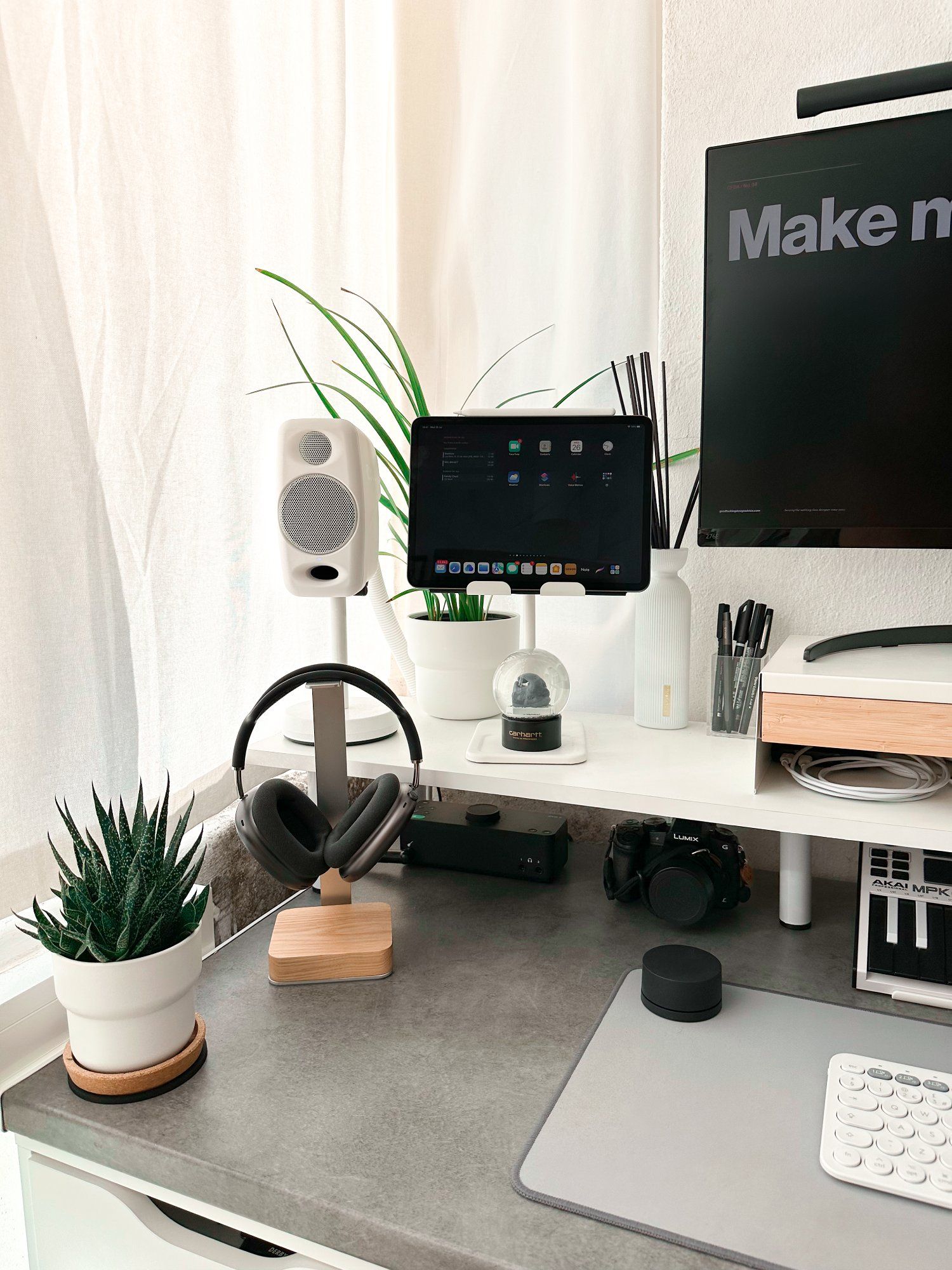A corner of a small, productive WFH desk setup featuring AirPods Max headphones hanging on a stand