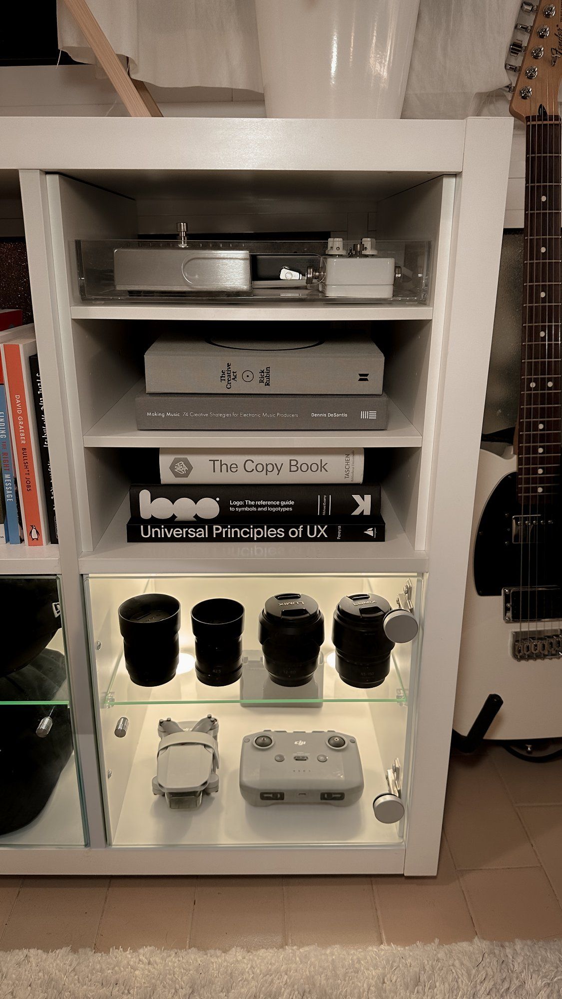 A close-up photo of a display cabinet with books, lenses for a digital camera, and a drone