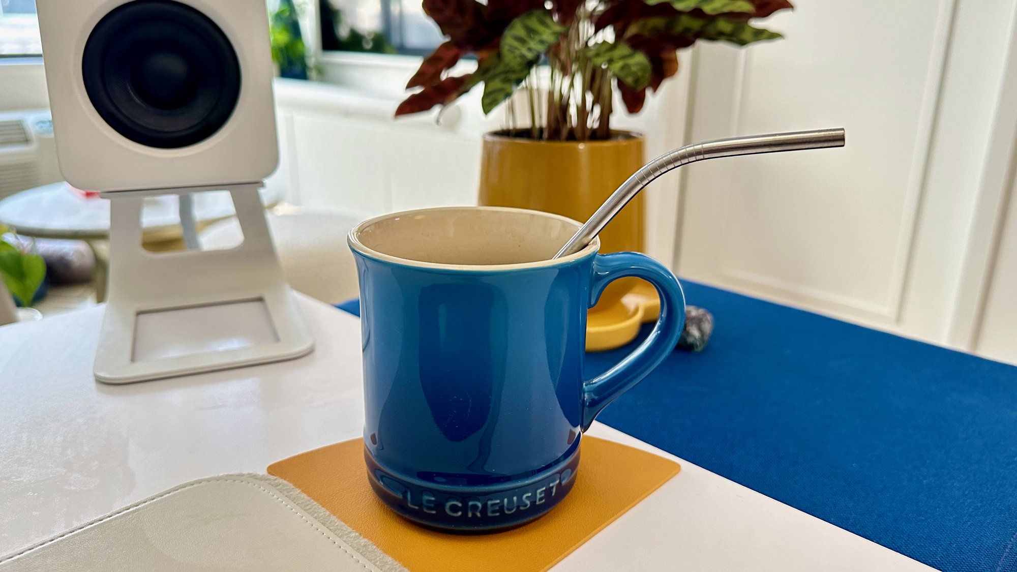 A blue Le Creuset mug on a yellow tea coaster