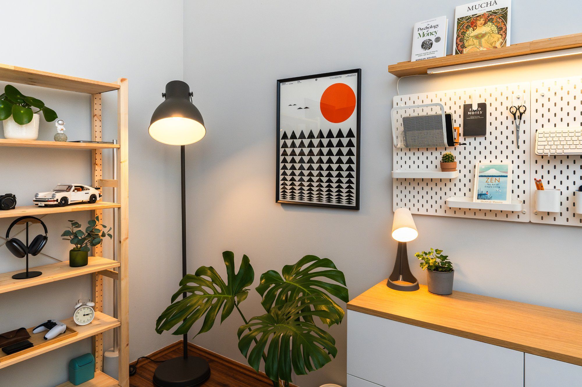 The corner of a home office showcases a bookcase and a Monstera plant, illuminated by an IKEA HEKTAR floor lamp