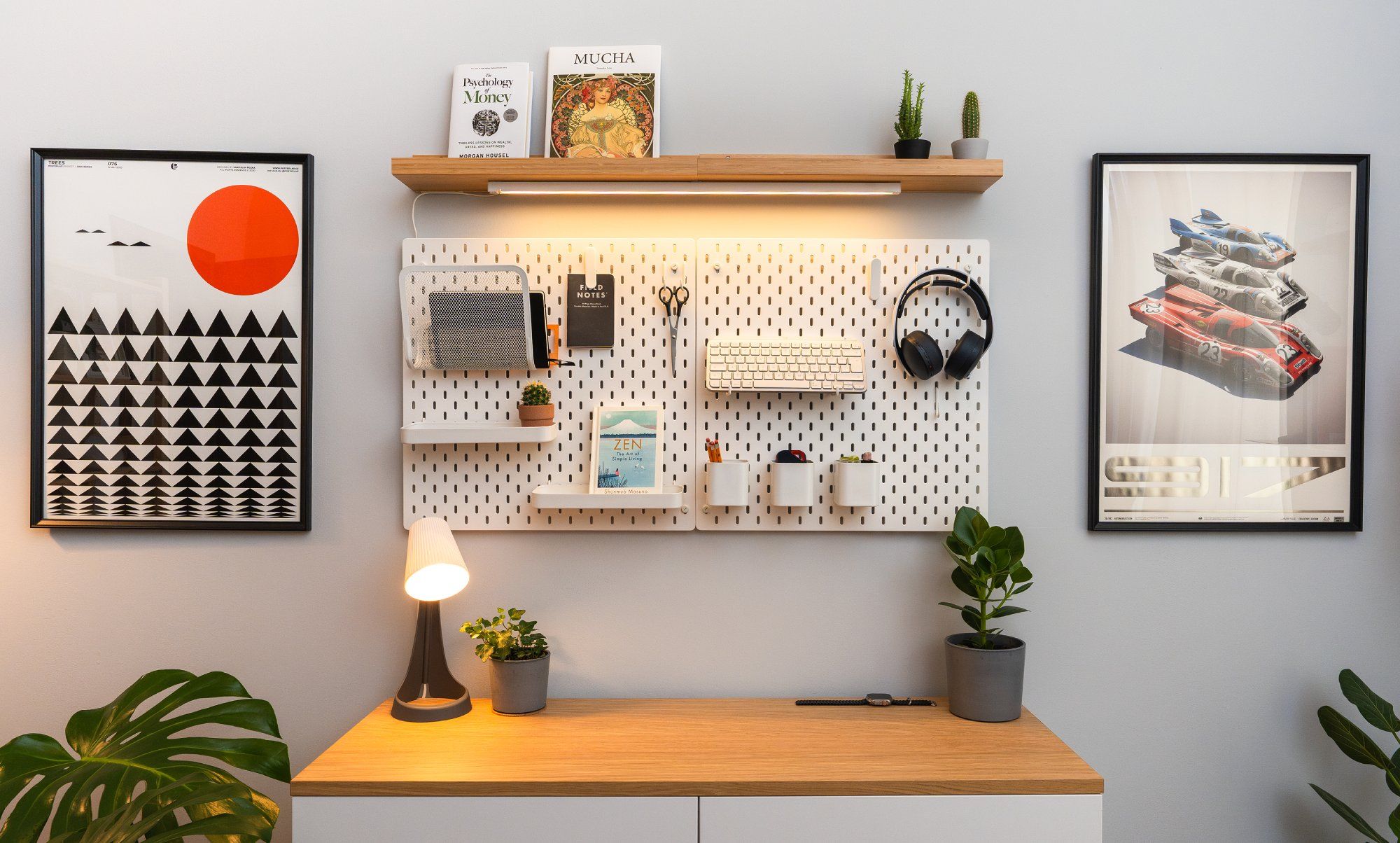 Một góc của văn phòng tại nhà tối giản có hai tấm bảng để đựng văn phòng phẩm và phụ kiện, được bổ sung bởi cây trồng trong nhà và tác phẩm nghệ thuật treo tường.
