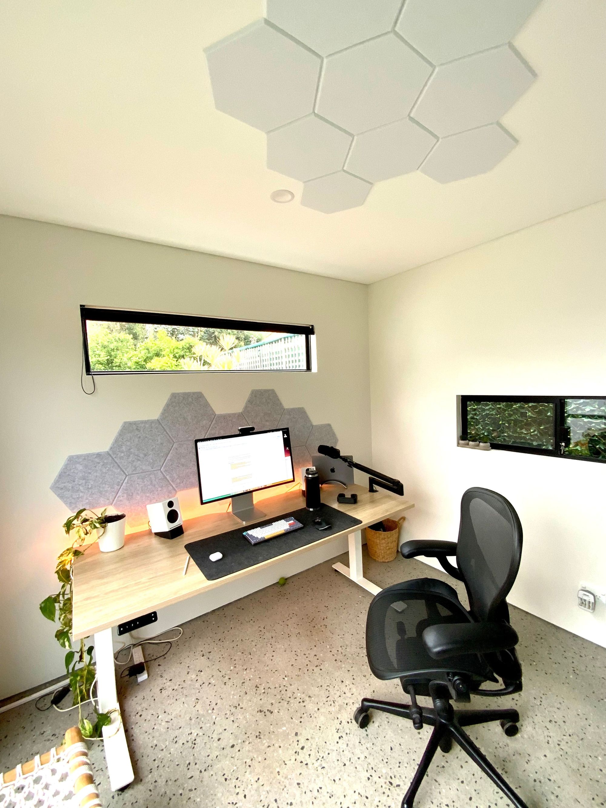 A small and ergonomic home office with acoustic tiles on the wall and ceiling
