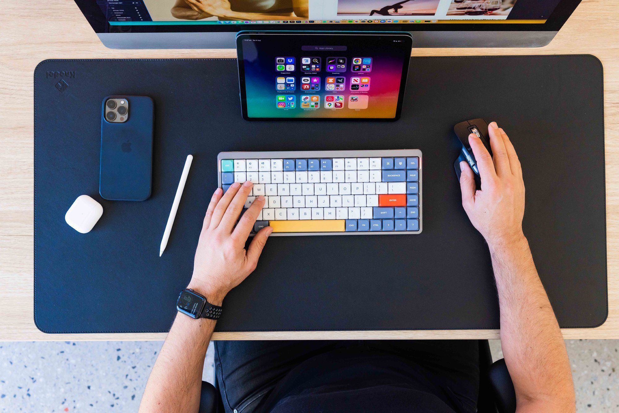 A top view of the desk setup with a NuPhy Air75 keyboard and Logitech MX Master 3 mouse, with male hands above them