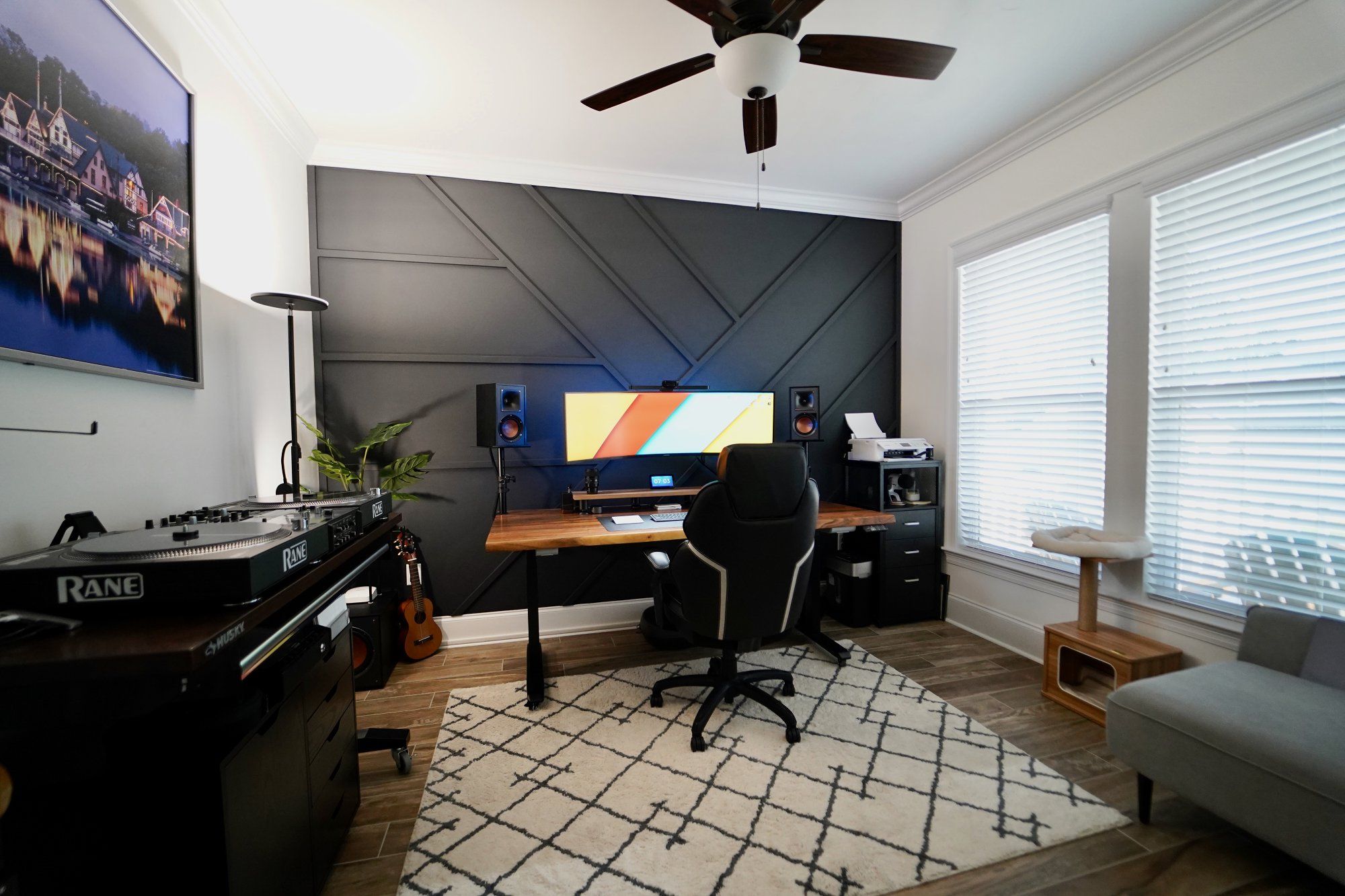 A well-designed home office with an ultrawide monitor, a cat house, and some DJ essentials